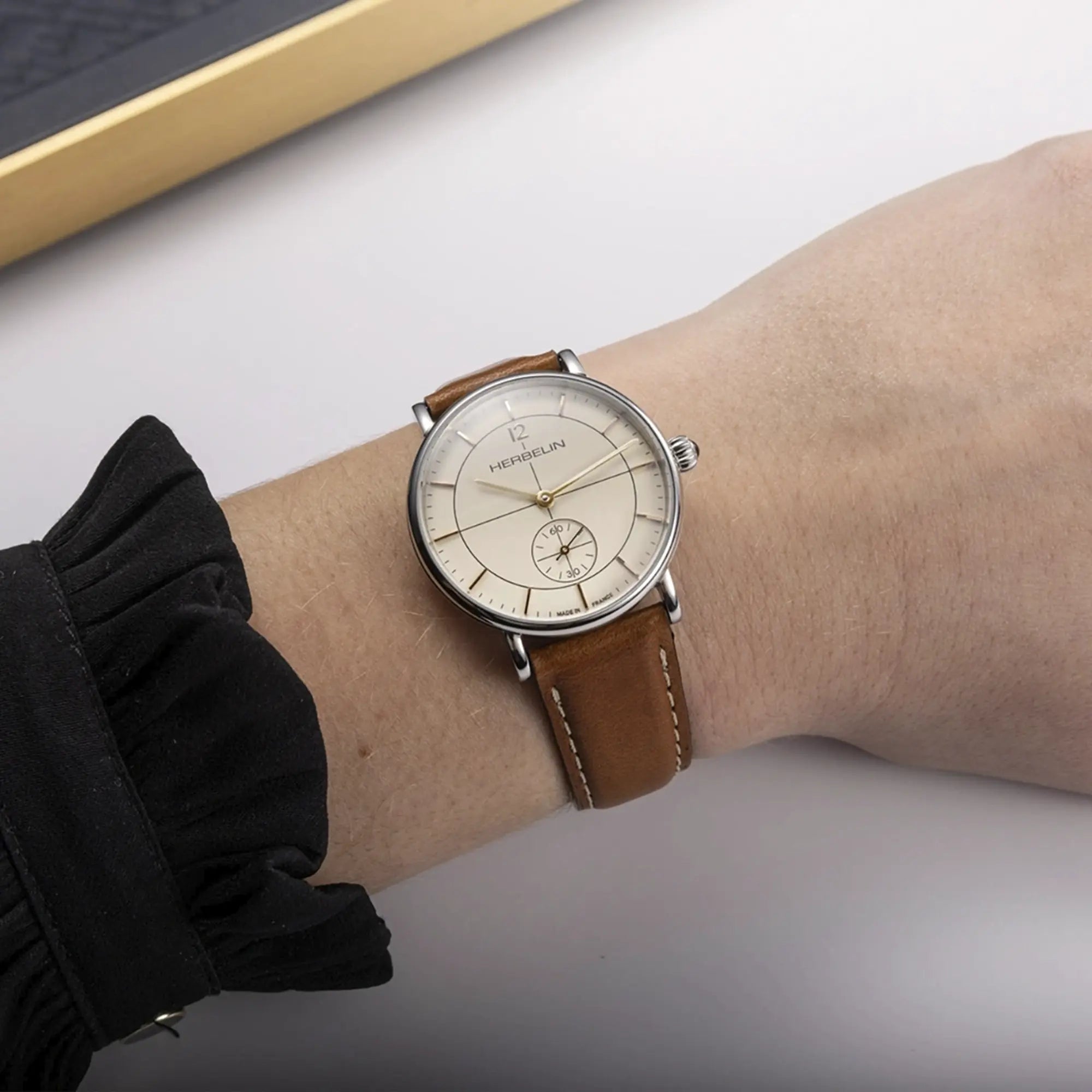 Au poignet féminin, cadran coquille d'œuf et bracelet cuir visibles