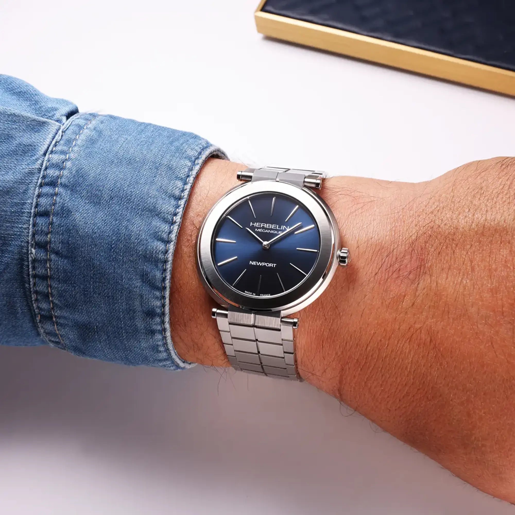 Au poignet masculin, cadran bleu et bracelet acier visibles