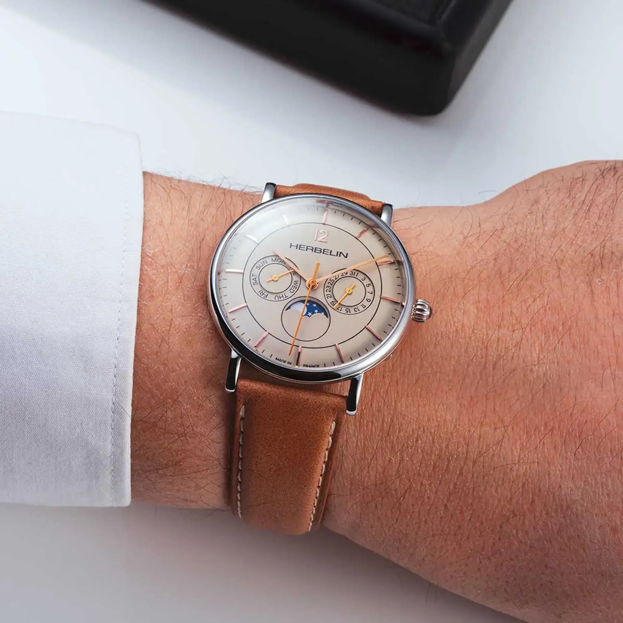 Au poignet masculin, cadran coquille d'œuf et bracelet cuir visibles