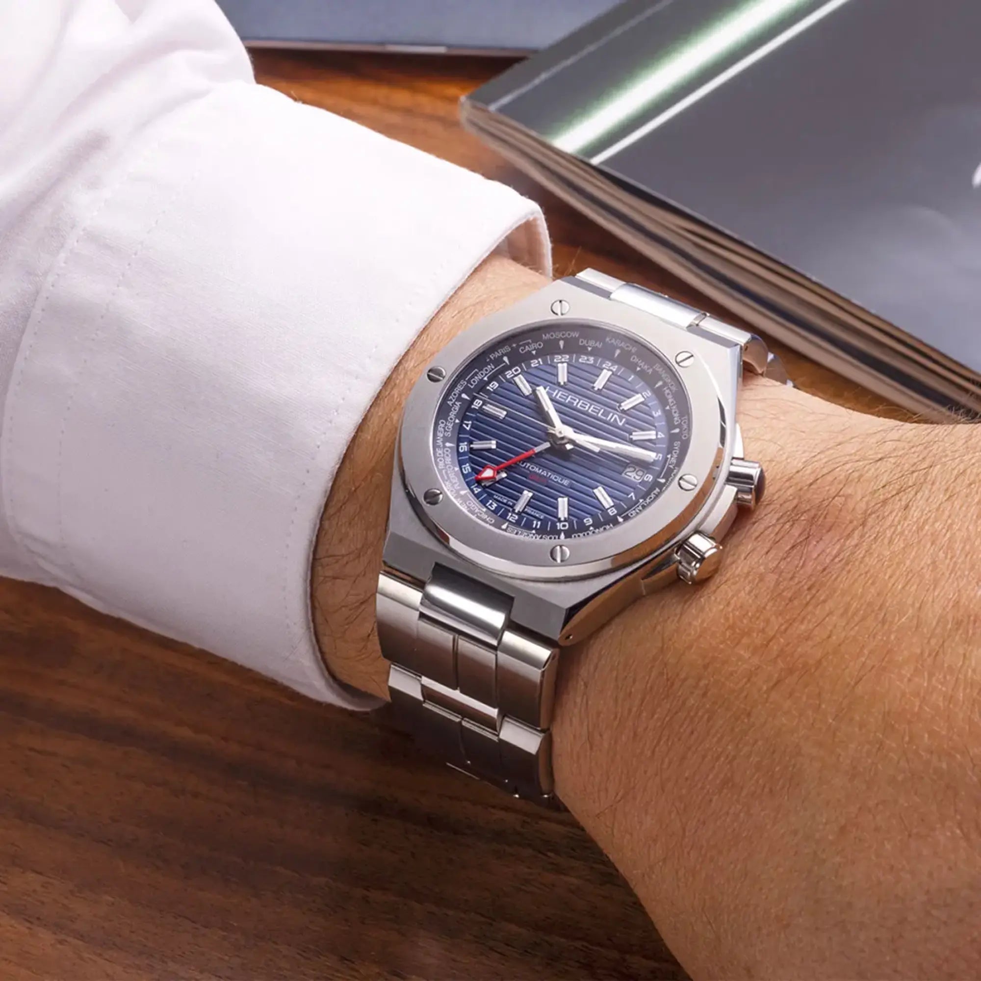 Au poignet masculin, cadran bleu et bracelet acier visibles