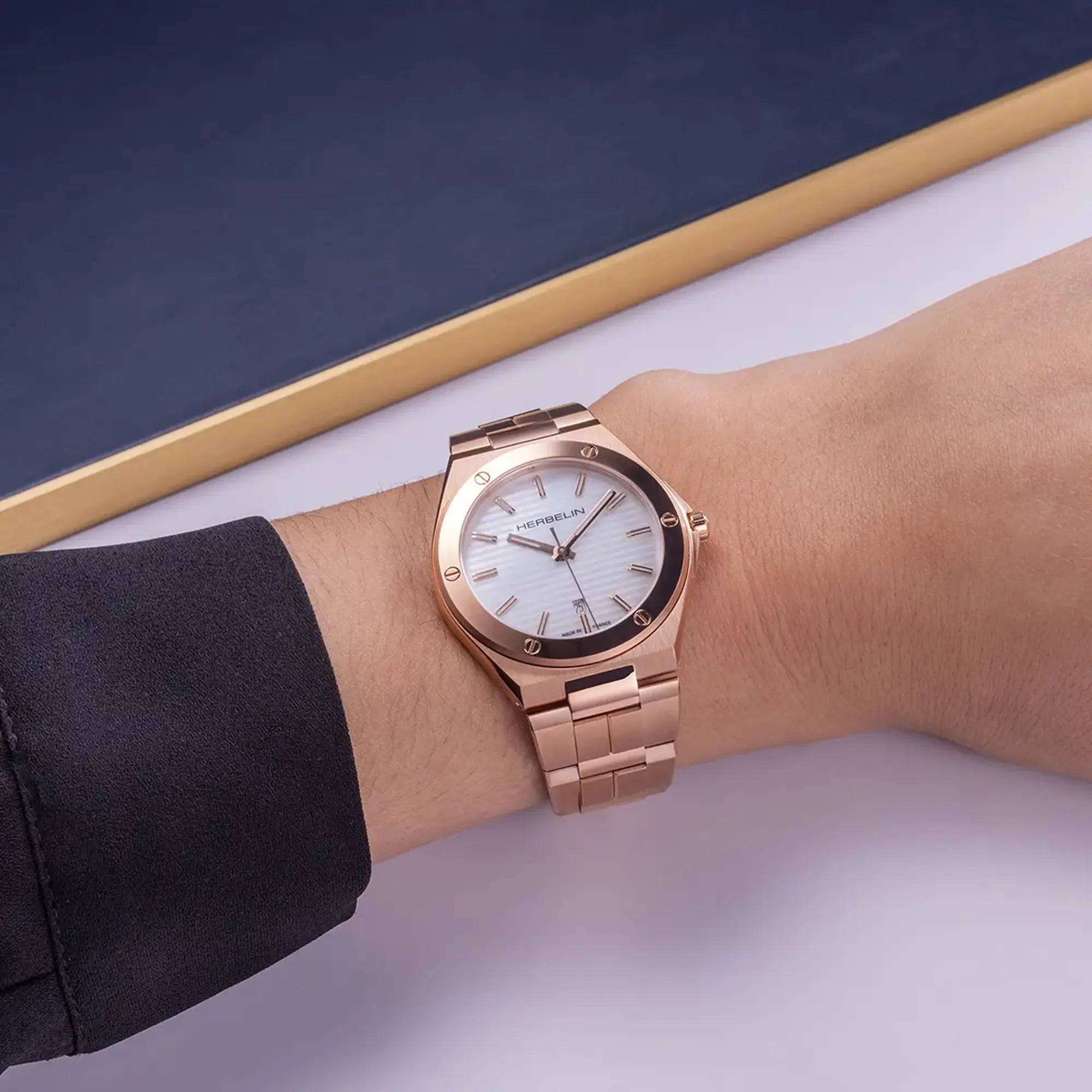 Au poignet féminin, cadran nacre blanche et bracelet acier PVD or rose visibles