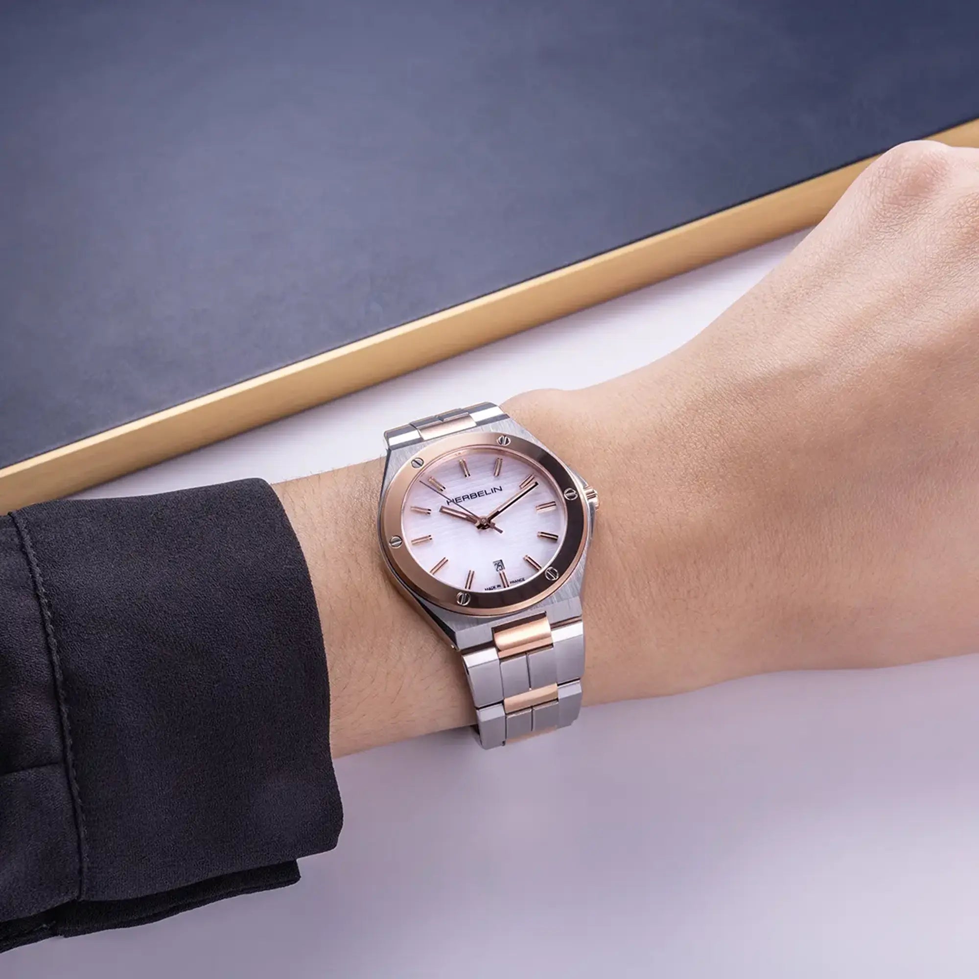 Au poignet féminin, cadran nacre blanche et bracelet acier PVD or rose visibles