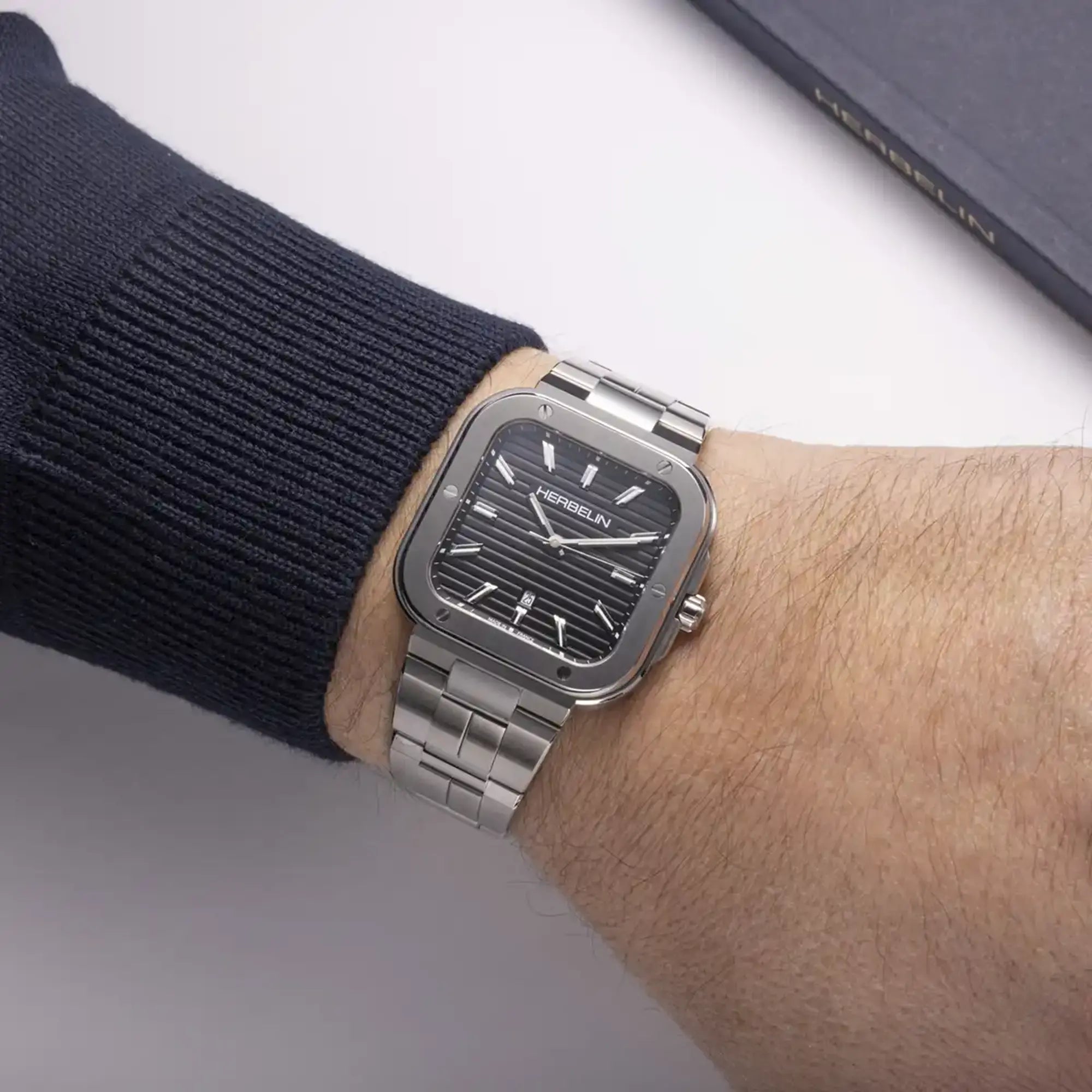 Au poignet masculin, cadran noir et bracelet acier visibles