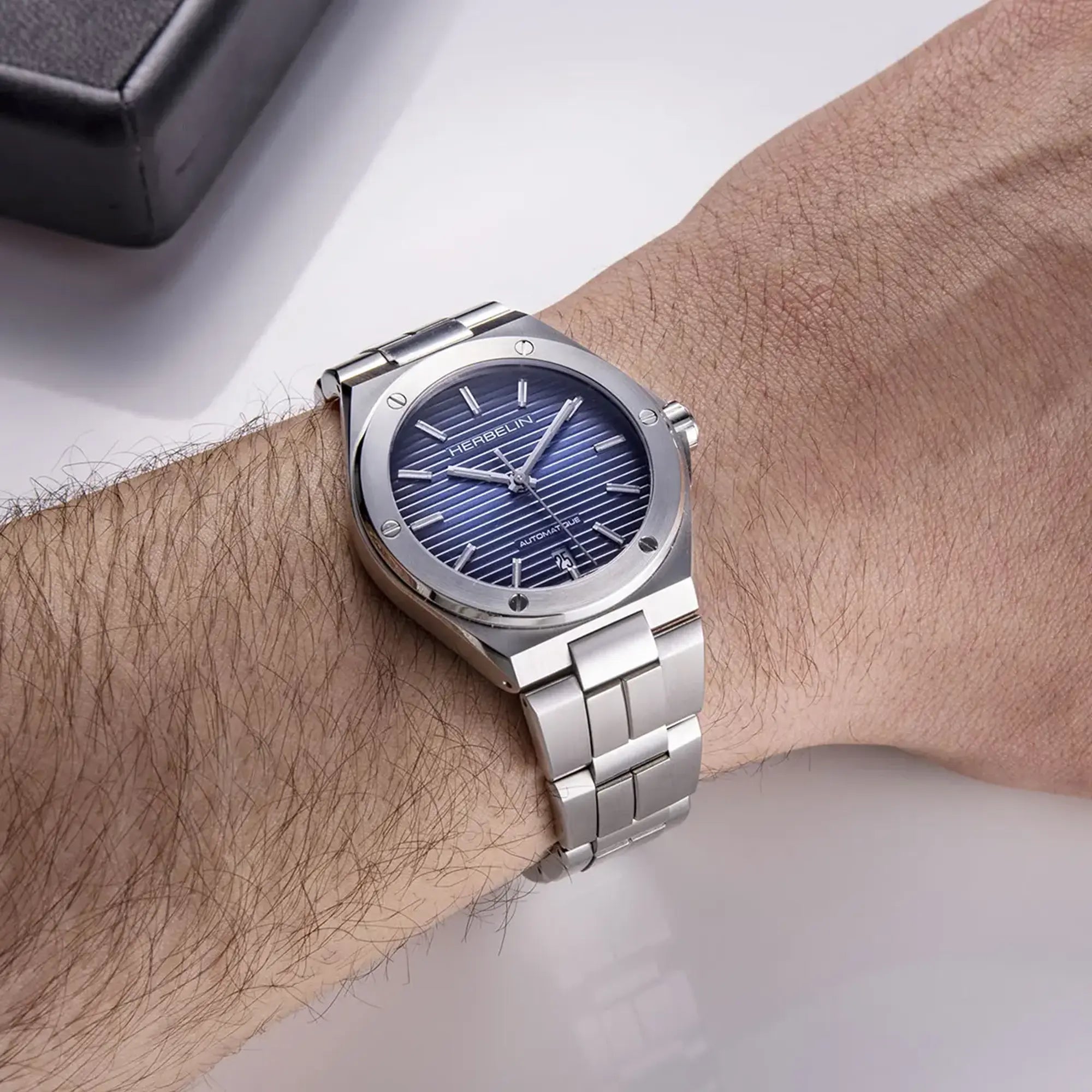 Au poignet masculin, cadran bleu dégradé et bracelet acier visibles