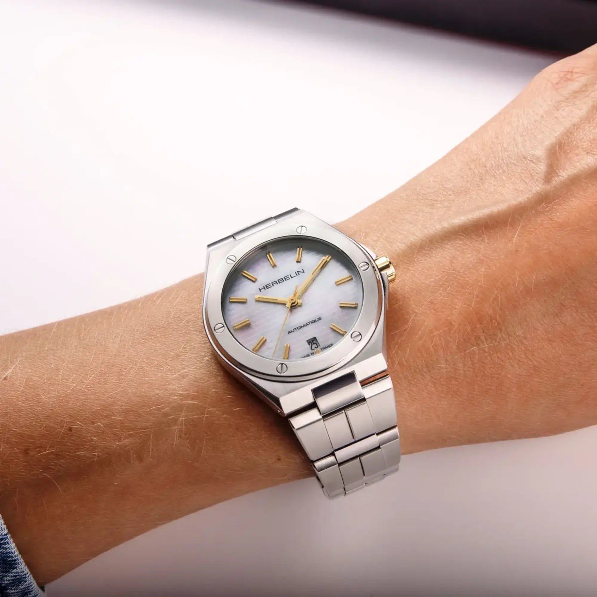 Au poignet féminin, cadran nacre blanche et bracelet acier visibles