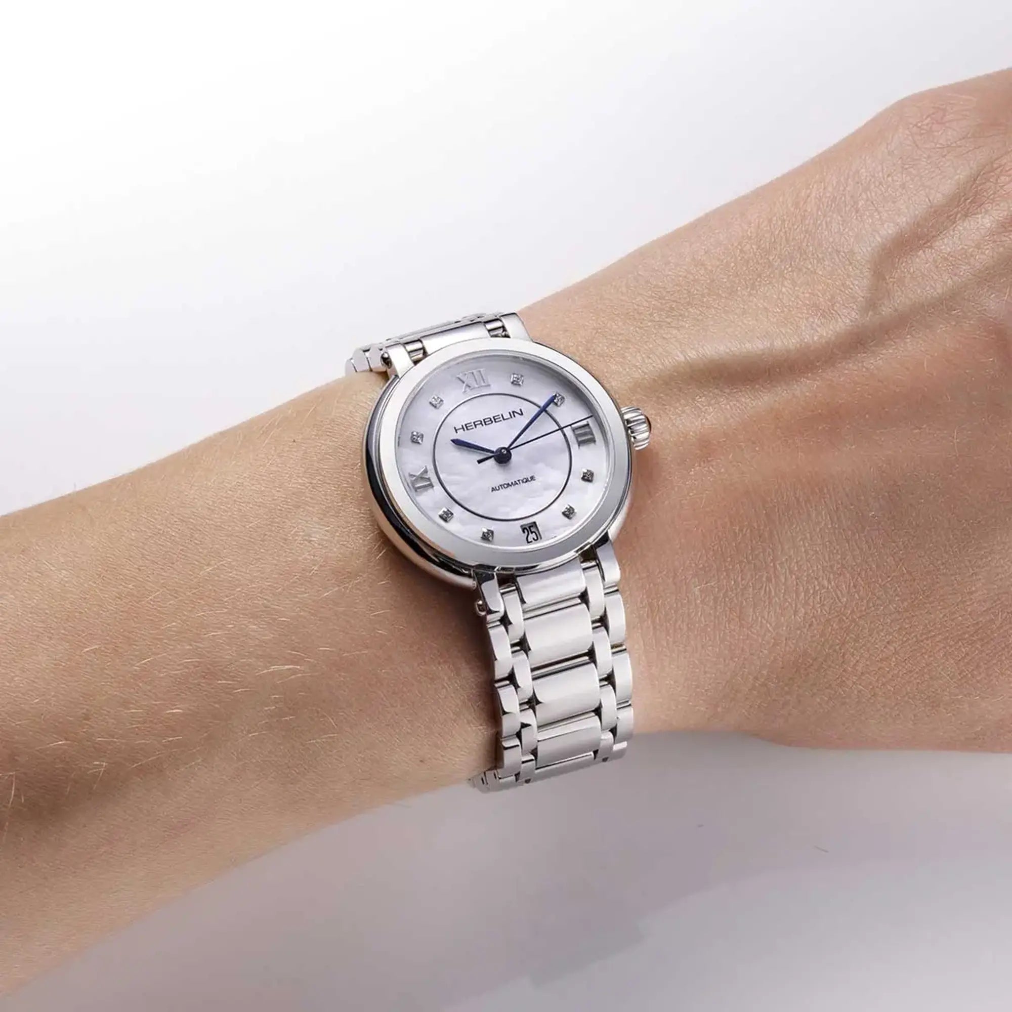 Au poignet féminin, cadran nacre blanche et bracelet acier visibles