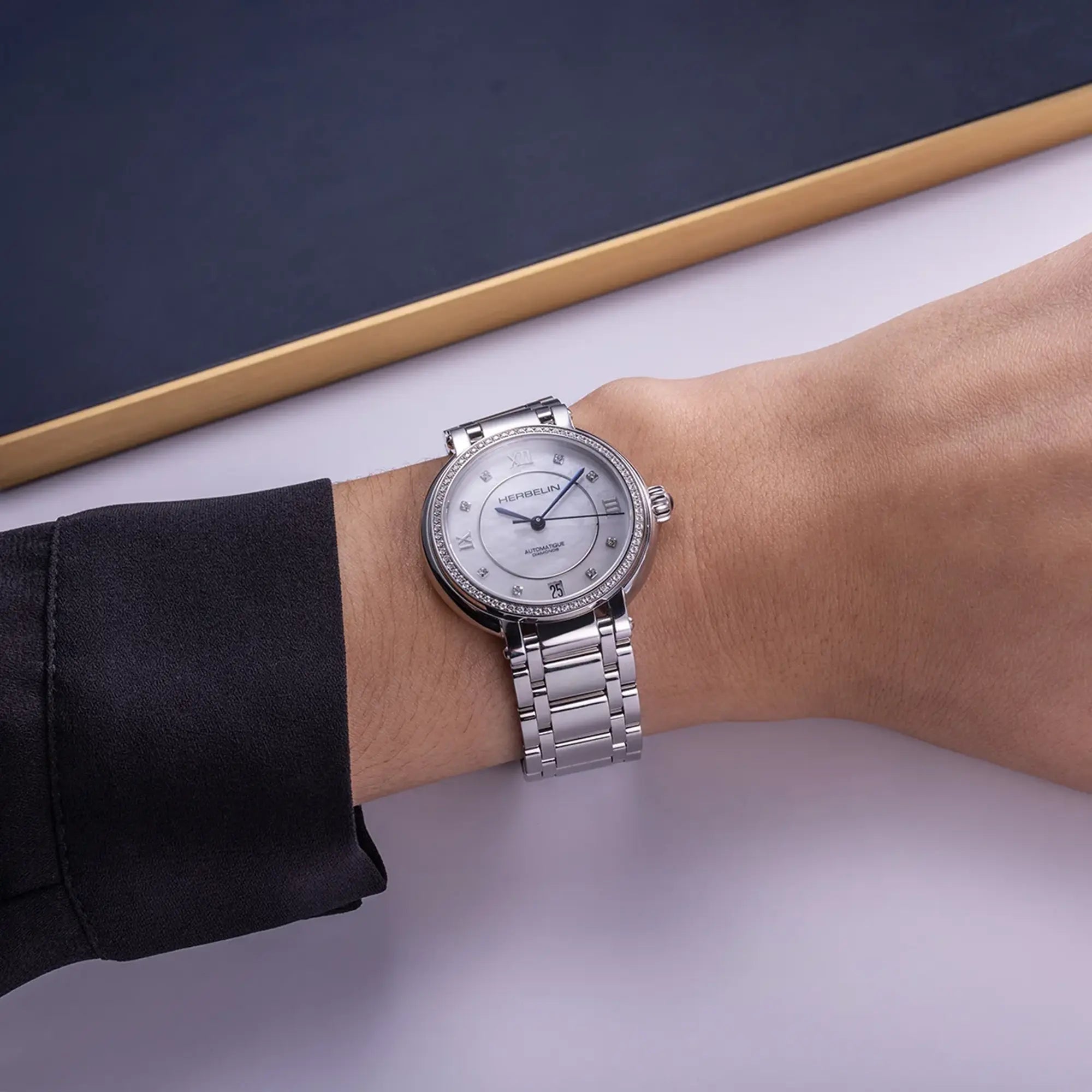 Au poignet féminin, cadran nacre blanche et bracelet acier visibles