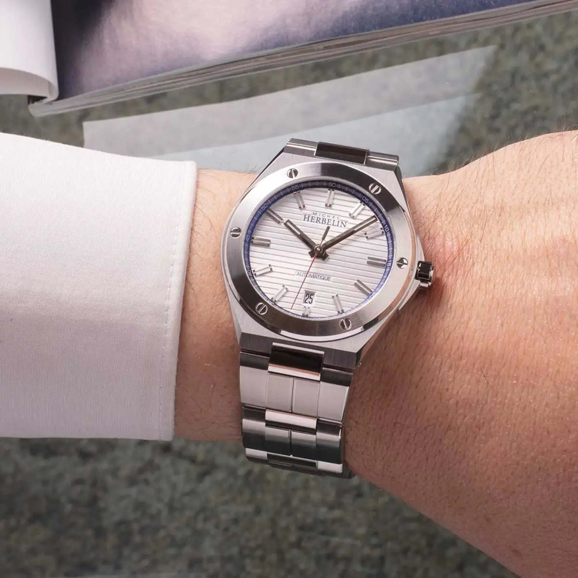 Au poignet masculin, cadran argent blanc et bracelet acier visibles