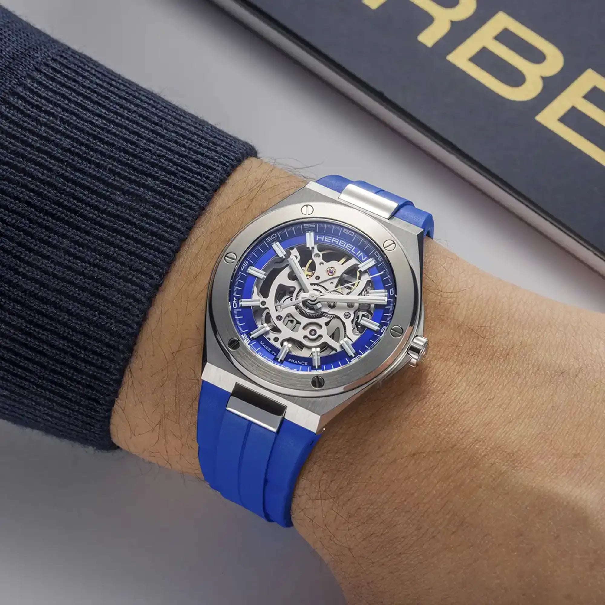 Au poignet masculin, cadran bleu cobalt et bracelet caoutchouc visibles