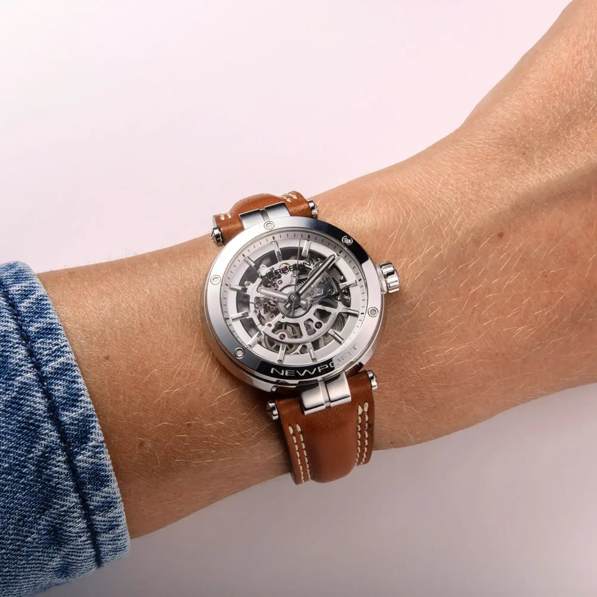 Au poignet féminin, cadran argent et bracelet cuir visibles