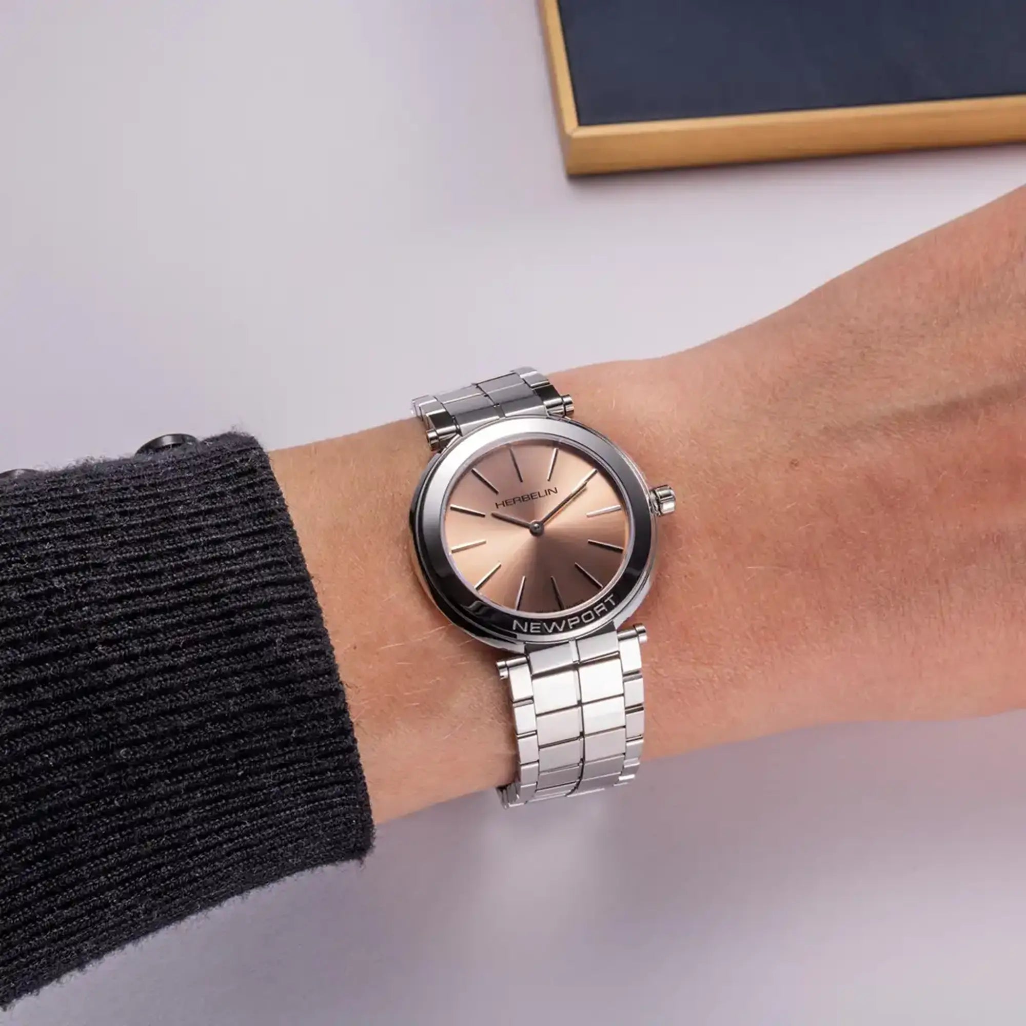 Au poignet féminin, cadran champagne rosé et bracelet acier visibles