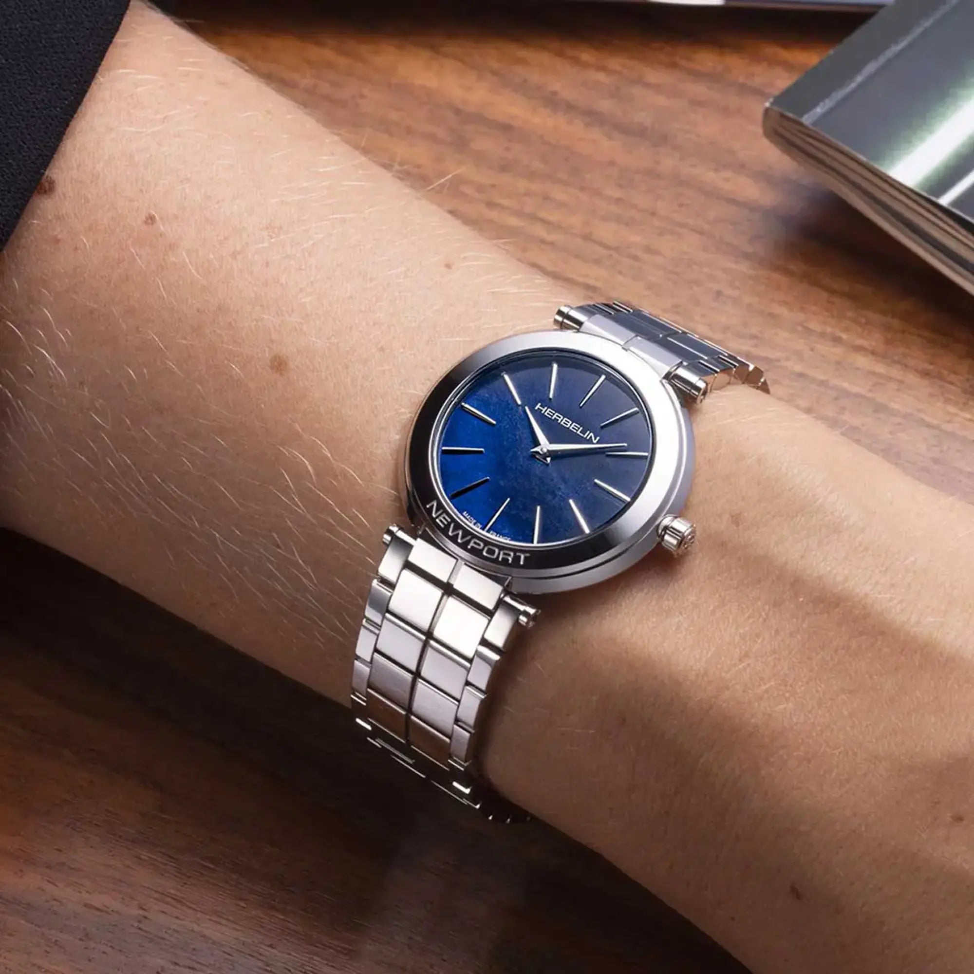 Au poignet féminin, cadran nacre bleue et bracelet acier visibles
