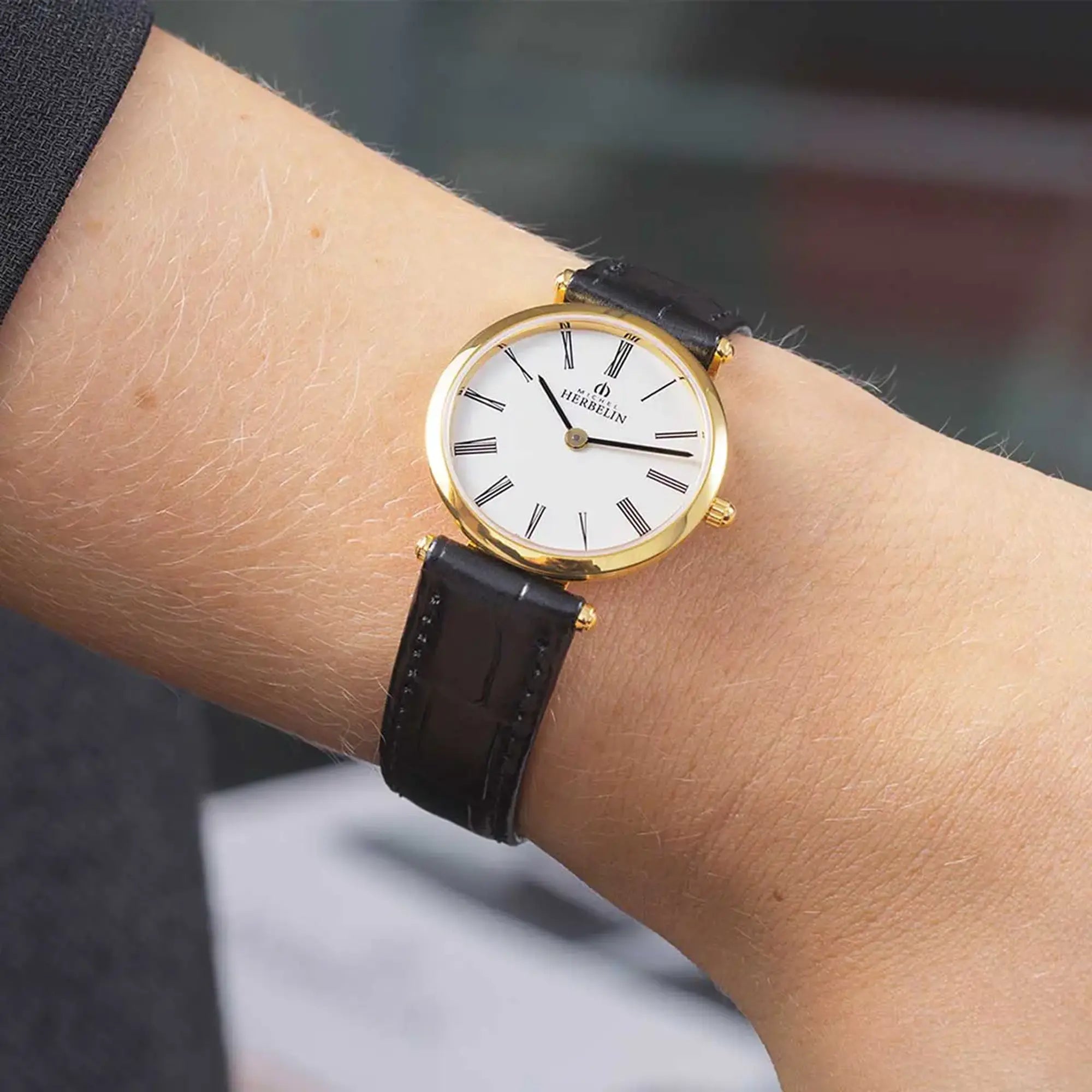 Au poignet féminin, cadran argent opalin et bracelet cuir visibles