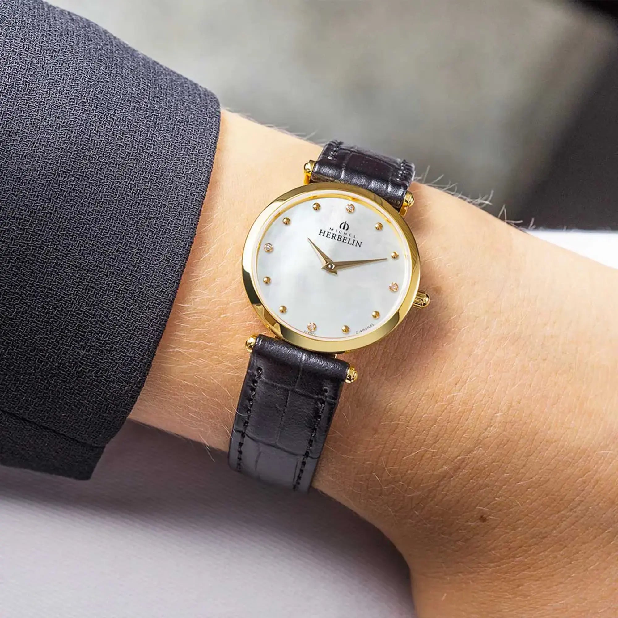 Au poignet féminin, cadran nacre blanche et bracelet cuir visibles