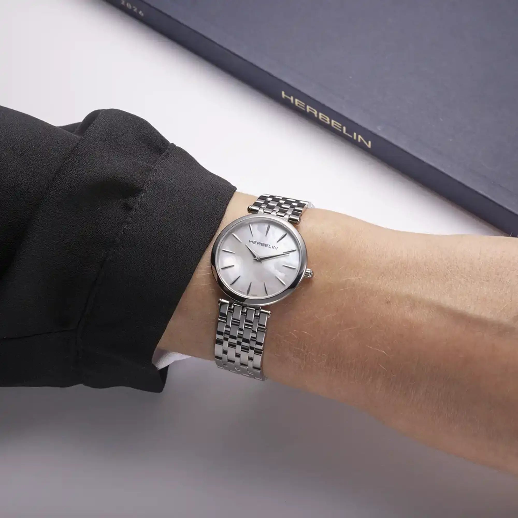 Au poignet féminin, cadran nacre blanche et bracelet acier visibles