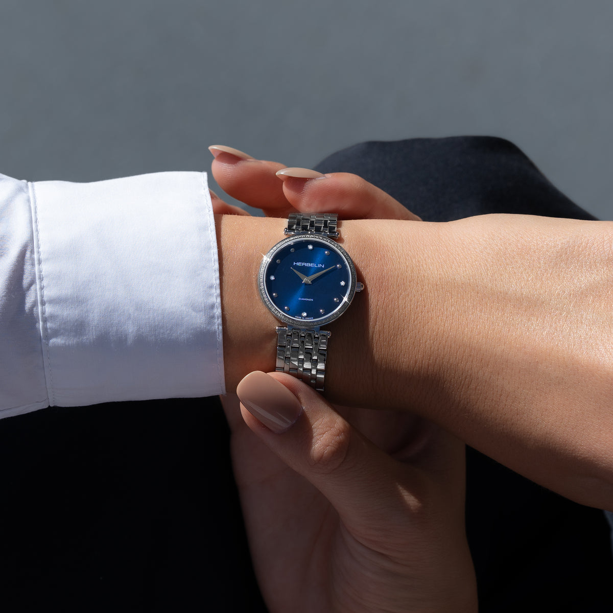 Au poignet féminin, cadran bleu et bracelet acier visibles