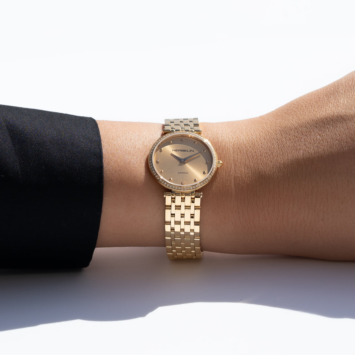 Au poignet féminin, cadran champagne et bracelet acier PVD or jaune visibles