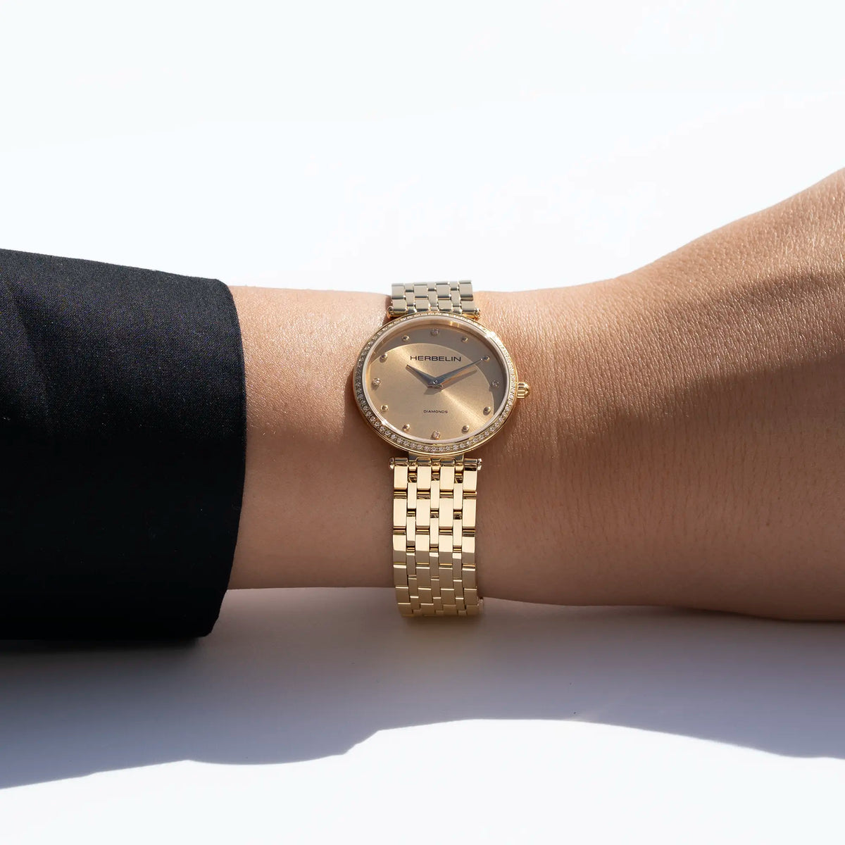 No pulso feminino, visível mostrador em champagne e bracelete em aço PVD ouro amarelo