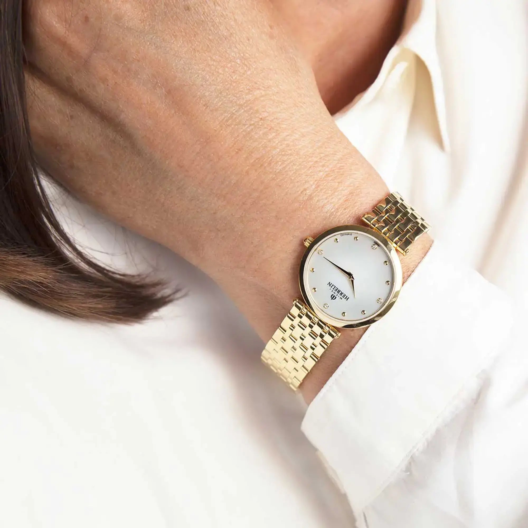 Au poignet féminin, cadran nacre blanche et bracelet acier bicolore visibles