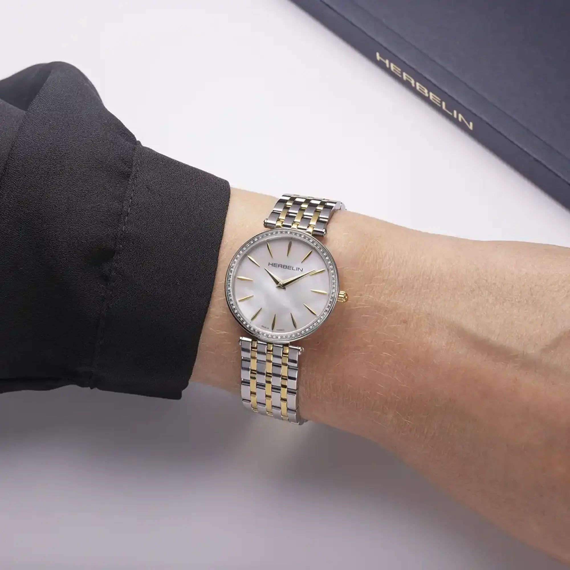 Au poignet féminin, cadran nacre blanche et bracelet acier bicolore visibles