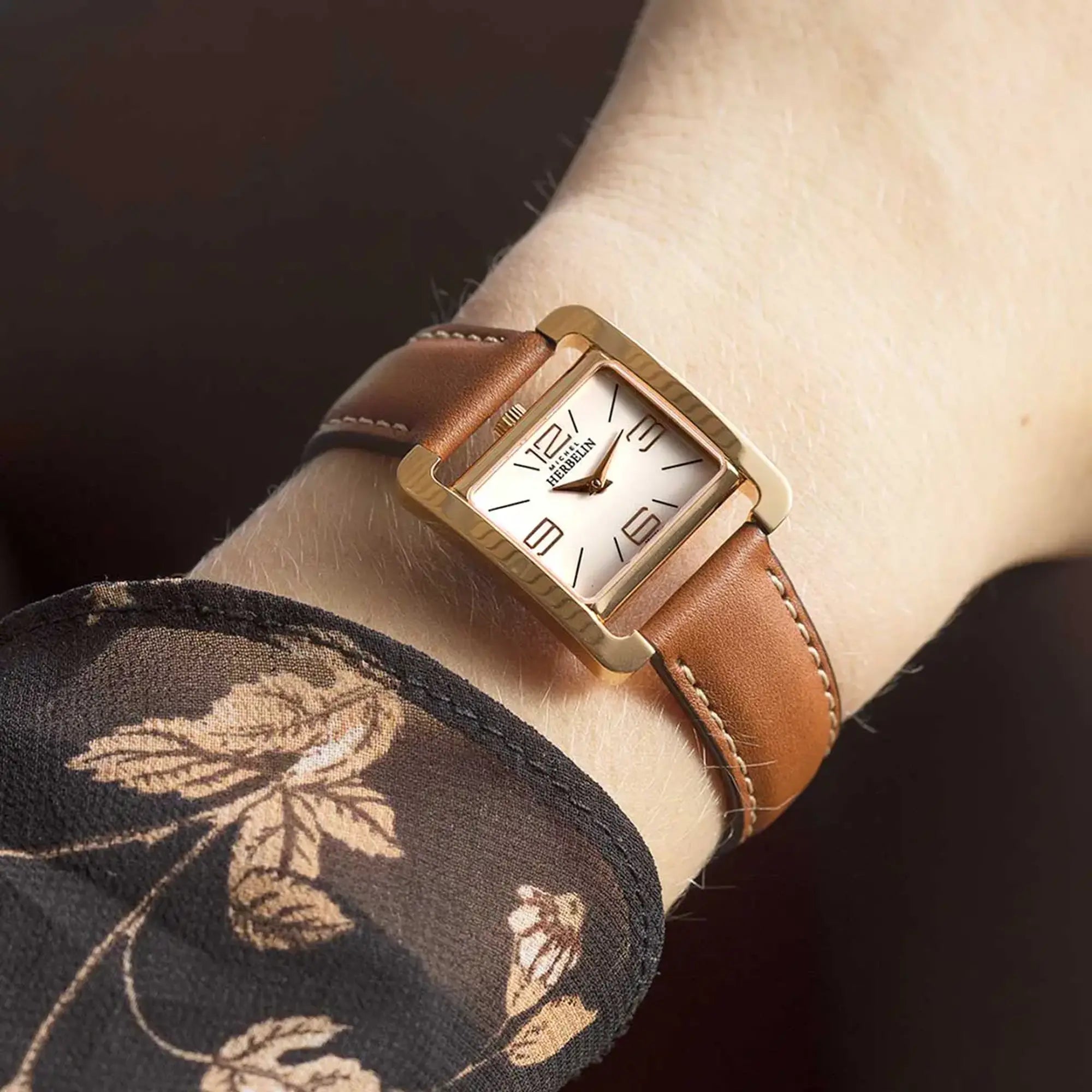 Au poignet féminin, cadran blanc laqué et bracelet cuir visibles