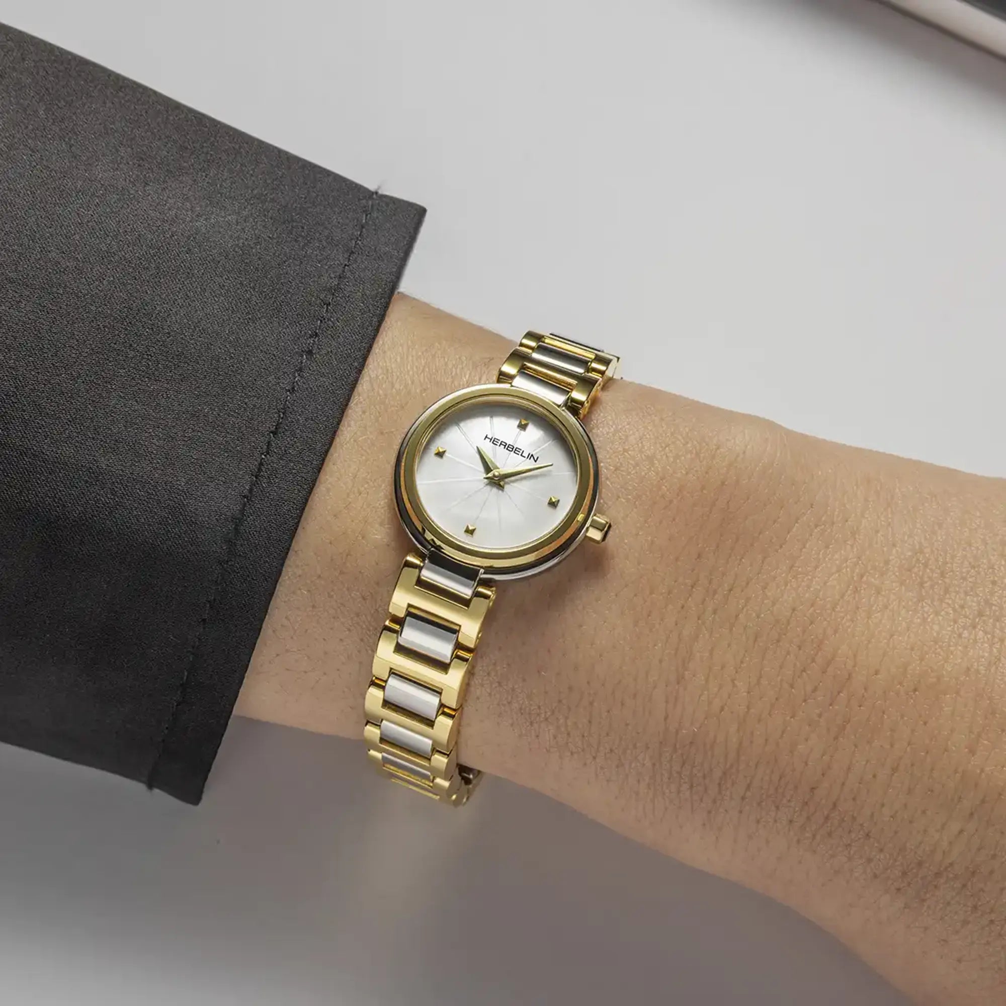 Au poignet féminin, cadran nacre blanche et bracelet acier bicolore visibles