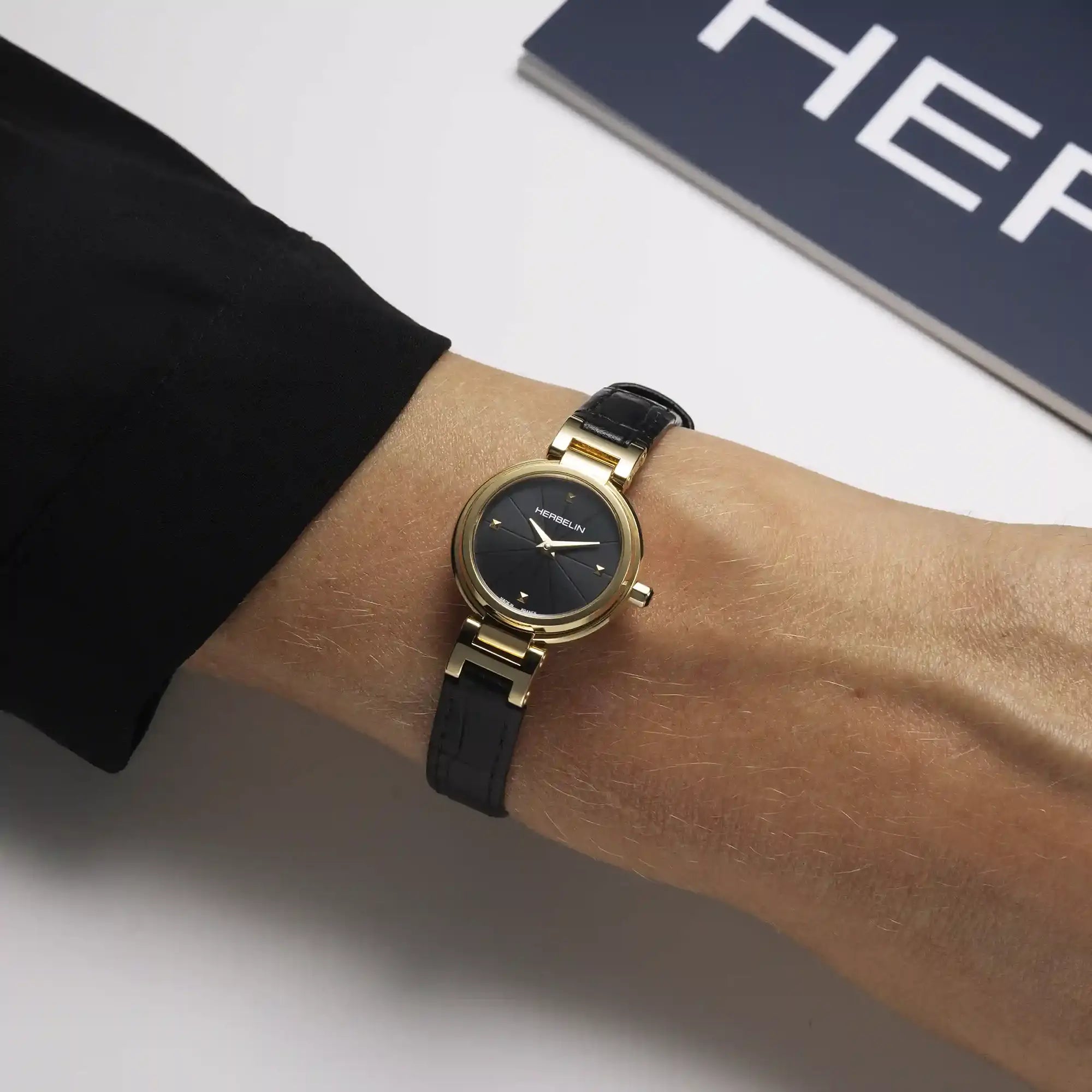 Au poignet féminin, cadran noir et bracelet cuir visibles