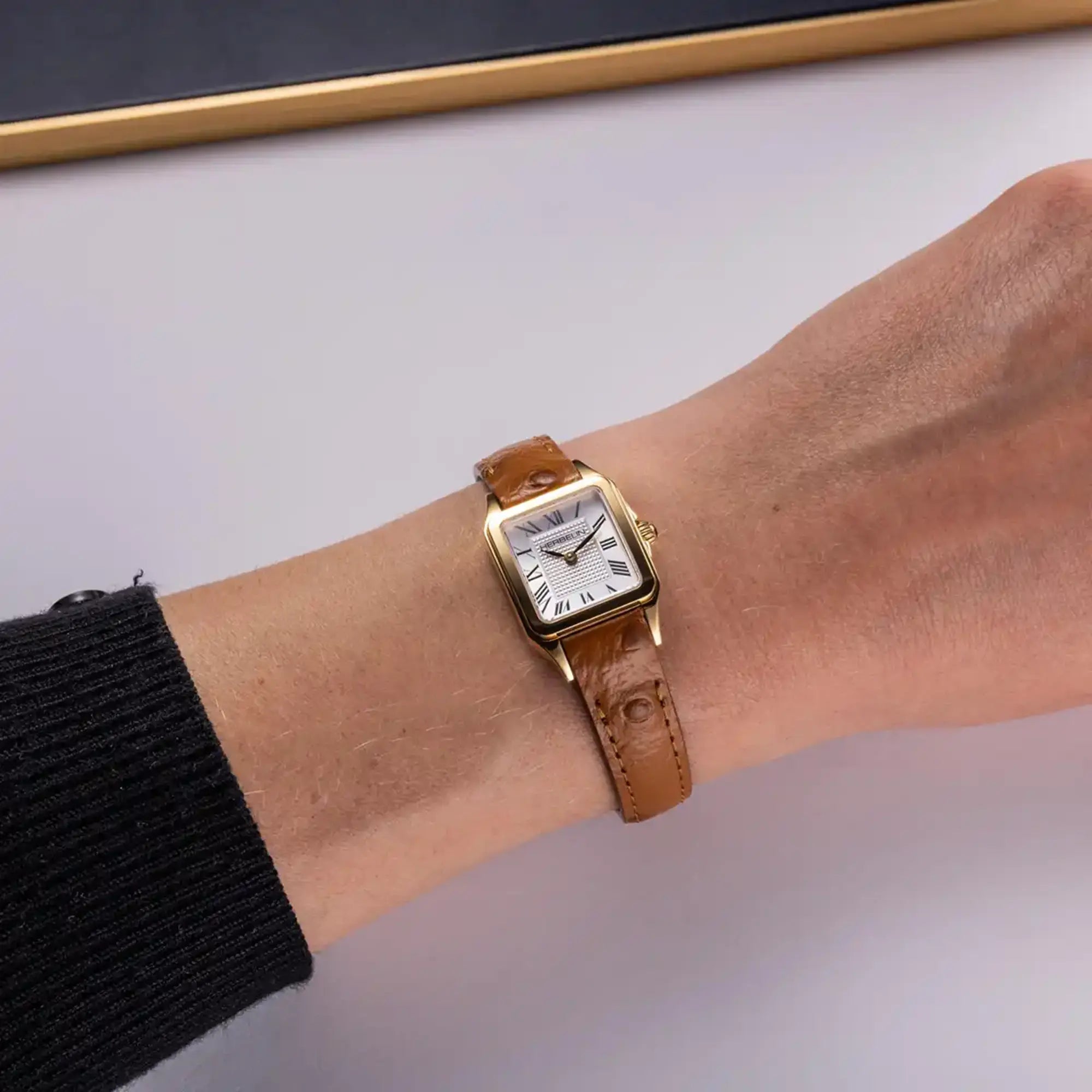 Au poignet féminin, cadran argent guilloché et bracelet cuir visibles