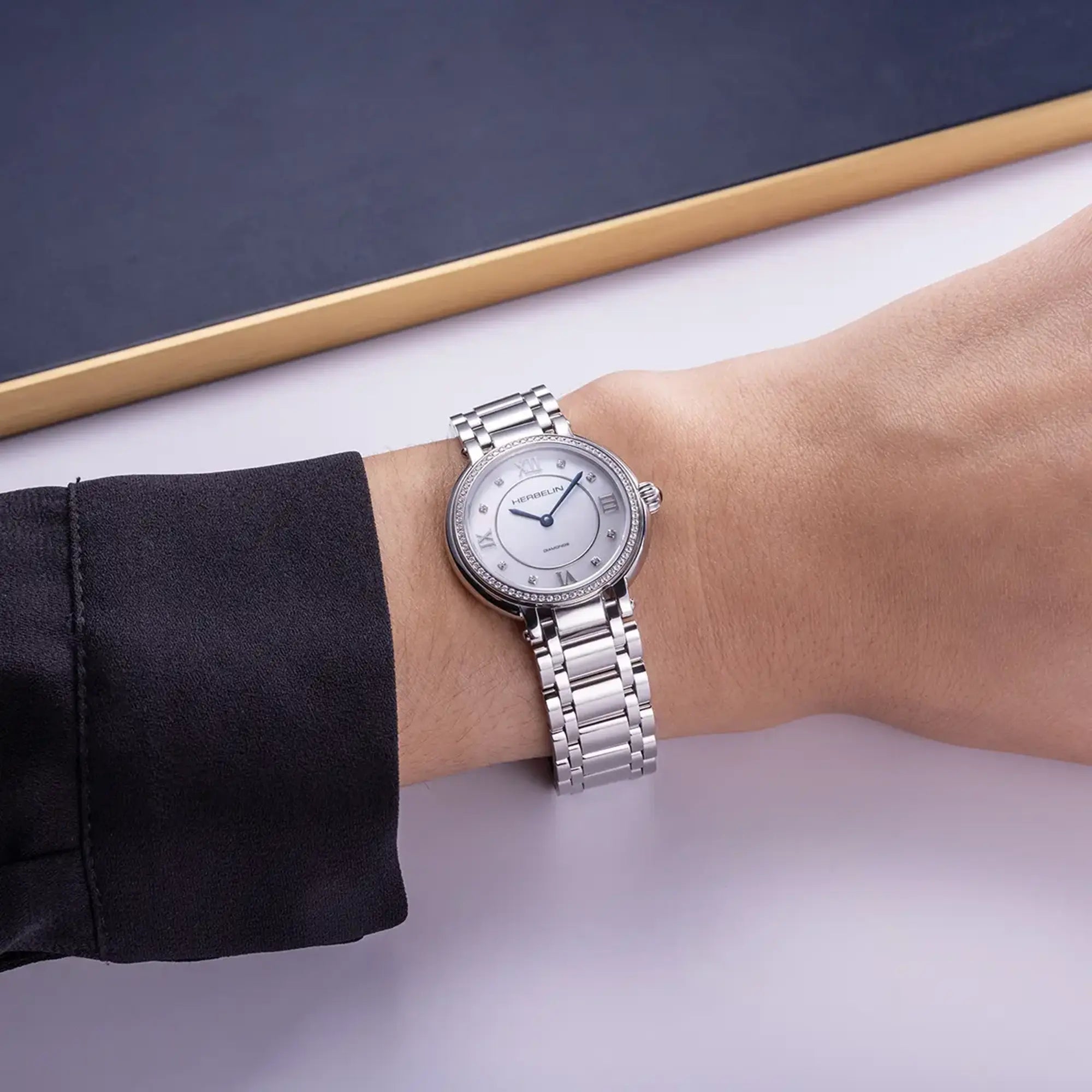 Au poignet féminin, cadran nacre blanche et bracelet acier visibles