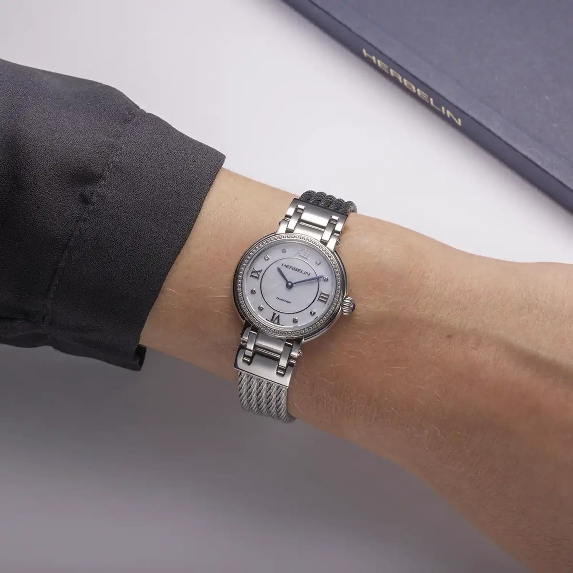 Au poignet féminin, cadran nacre blanche et bracelet acier visibles