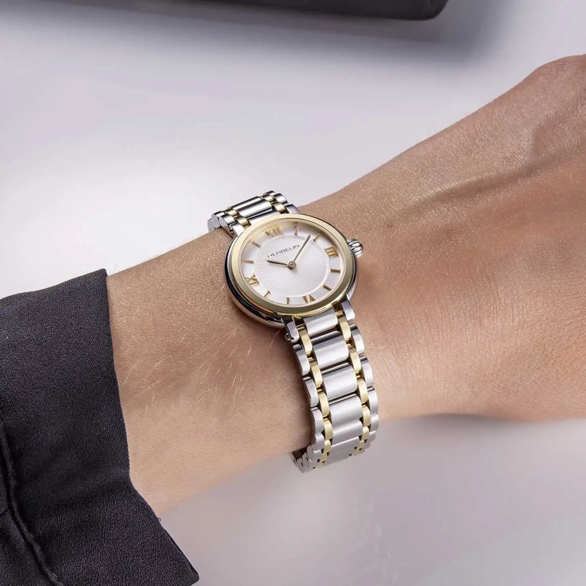 Au poignet féminin, cadran argent guilloché et bracelet acier bicolore visibles