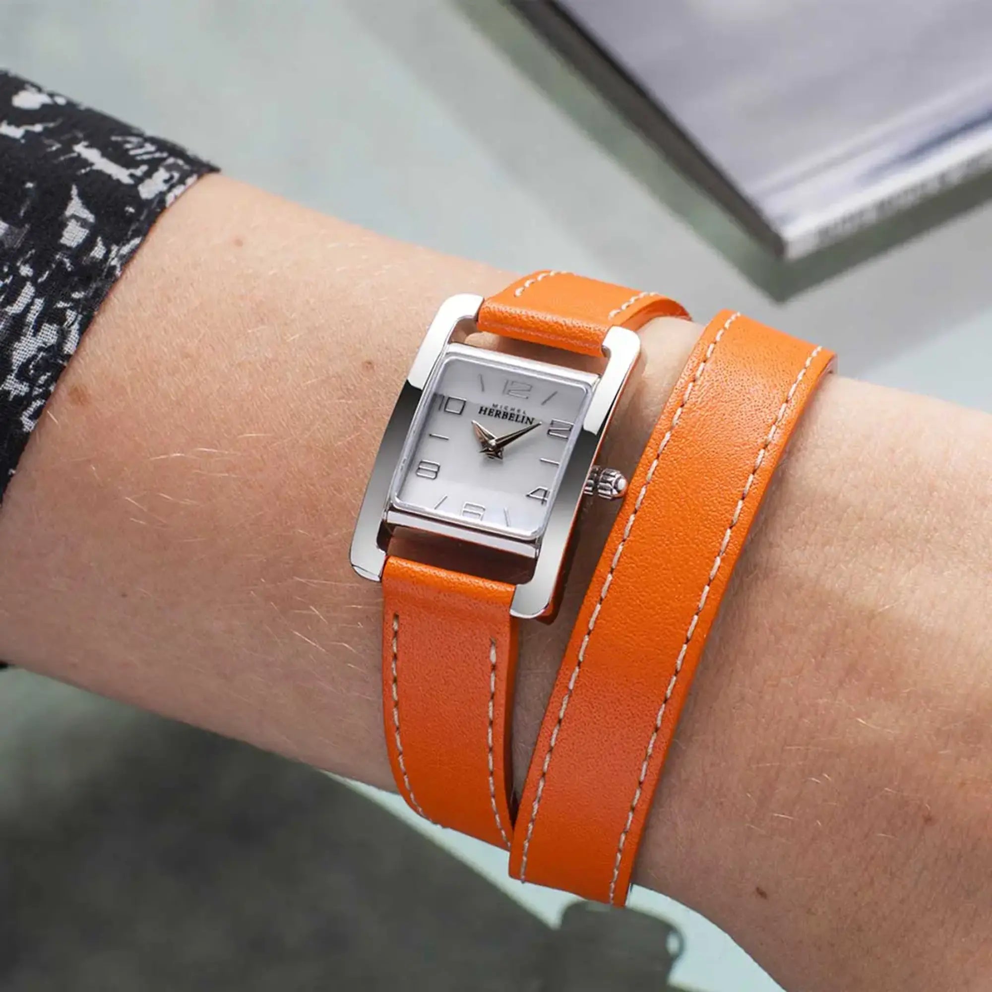 Au poignet féminin, cadran nacre blanche et bracelet cuir visibles
