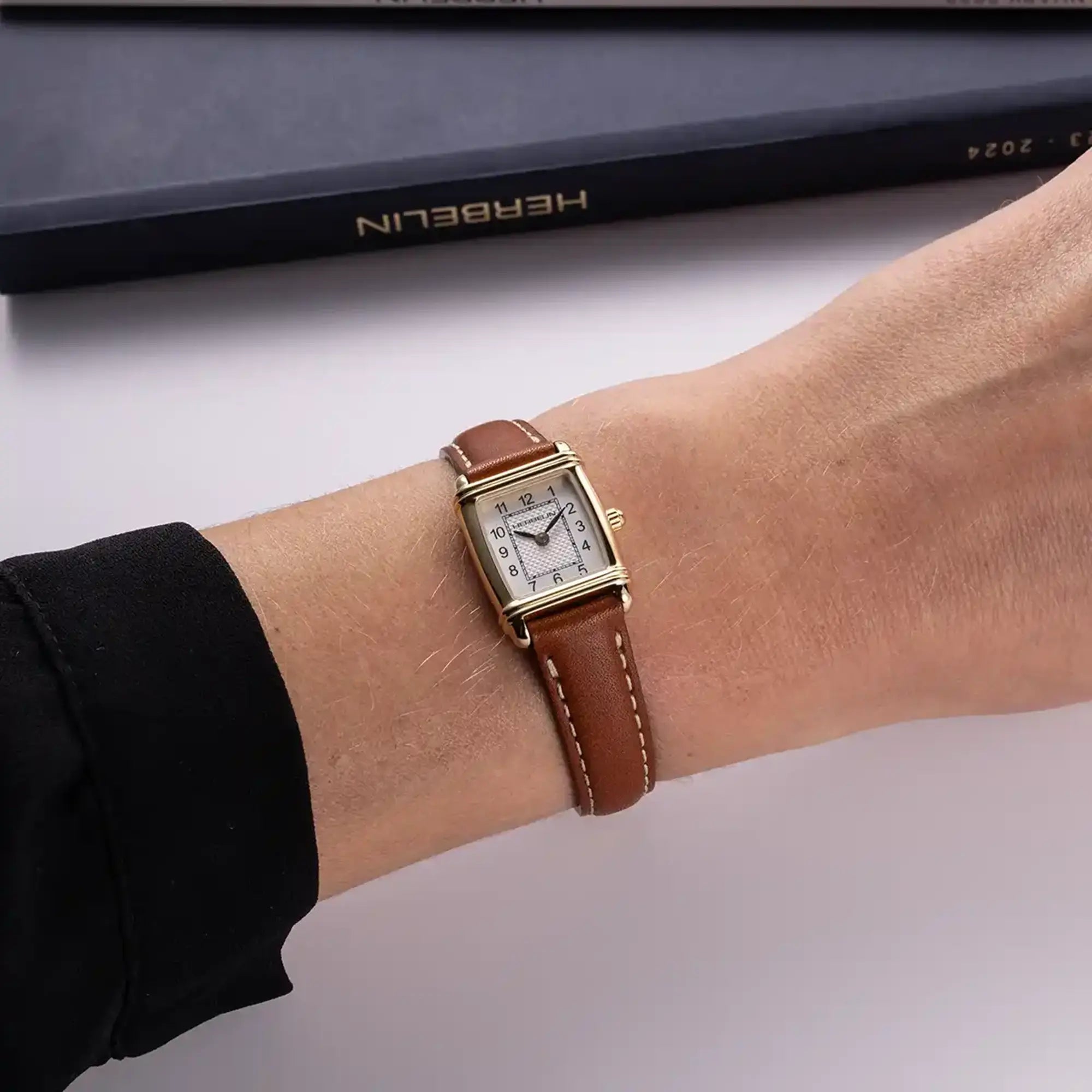 Au poignet féminin, cadran argent guilloché et bracelet cuir visibles