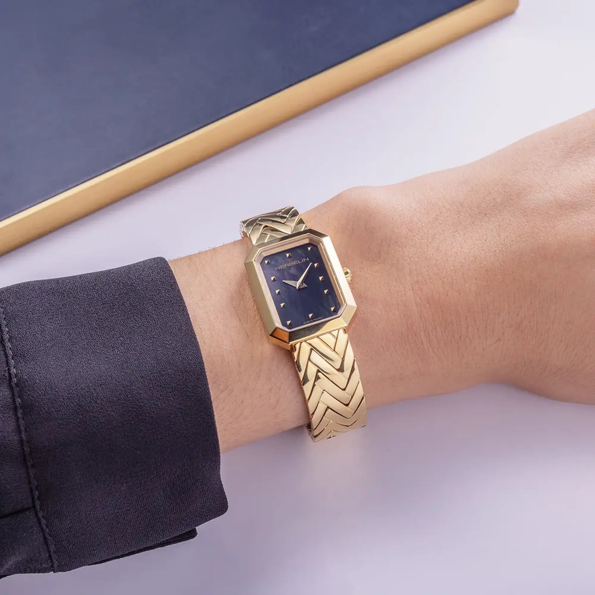 Au poignet féminin, cadran nacre noire et bracelet acier bicolore visibles