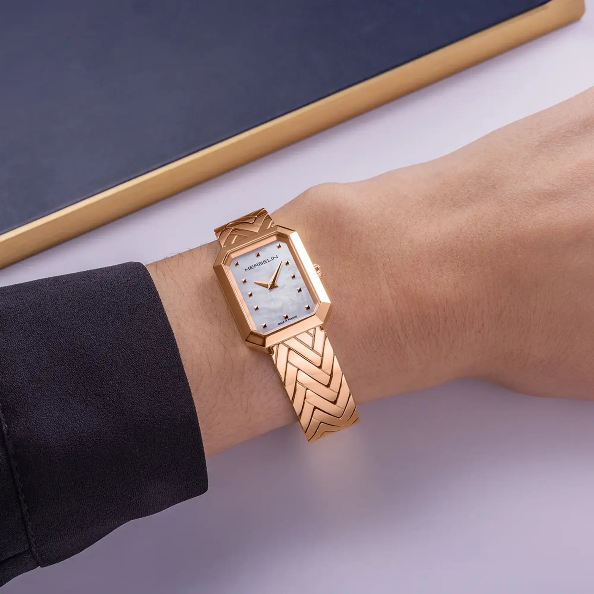 Au poignet féminin, cadran nacre blanche et bracelet acier PVD or rose visibles