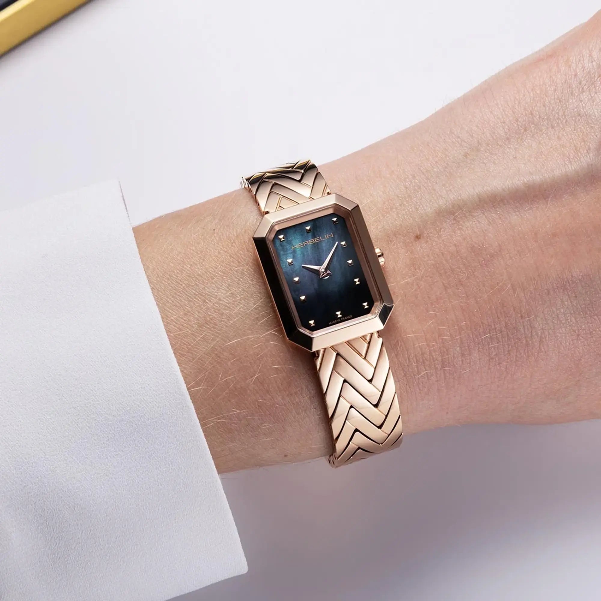 Au poignet féminin, cadran nacre noire et bracelet acier PVD or rose visibles