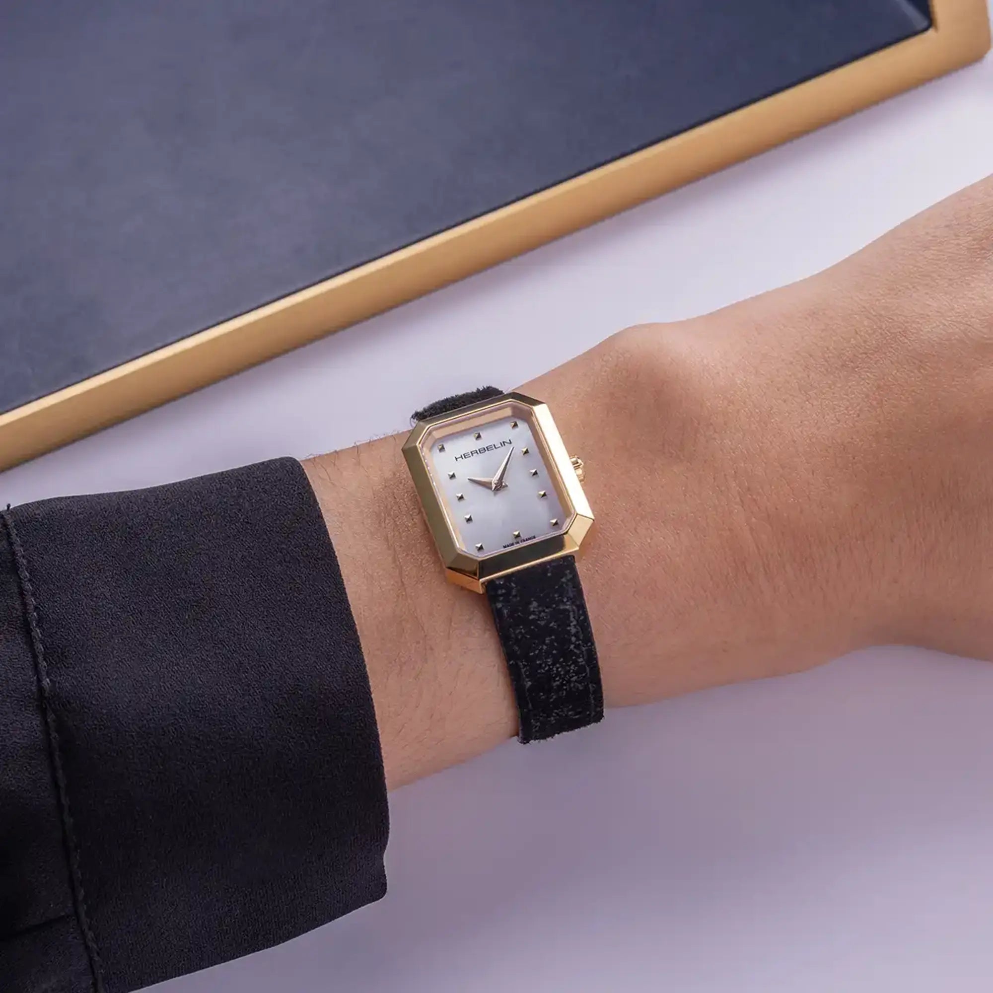 Au poignet féminin, cadran nacre blanche et bracelet cuir visibles