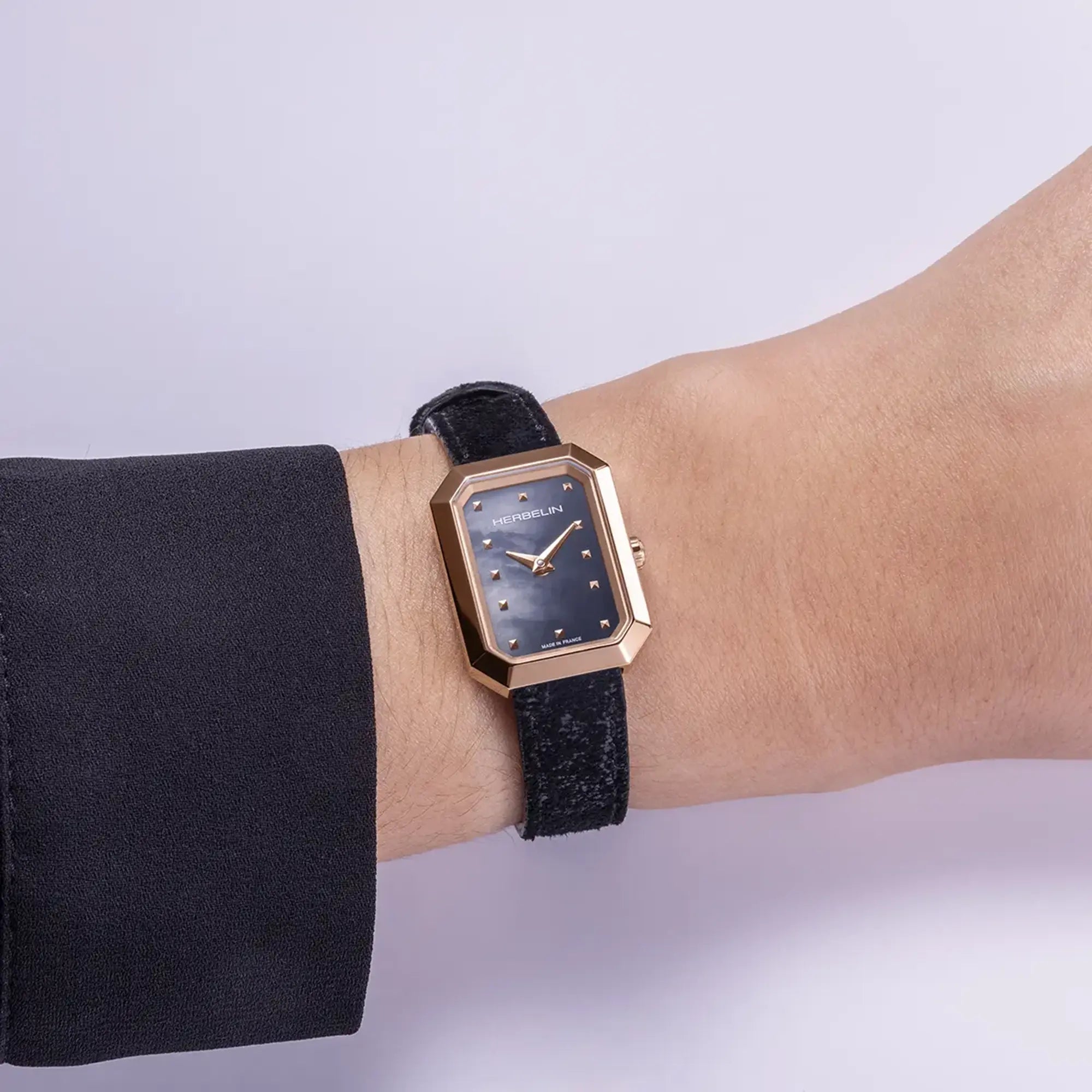 Au poignet féminin, cadran nacre noire et bracelet cuir visibles