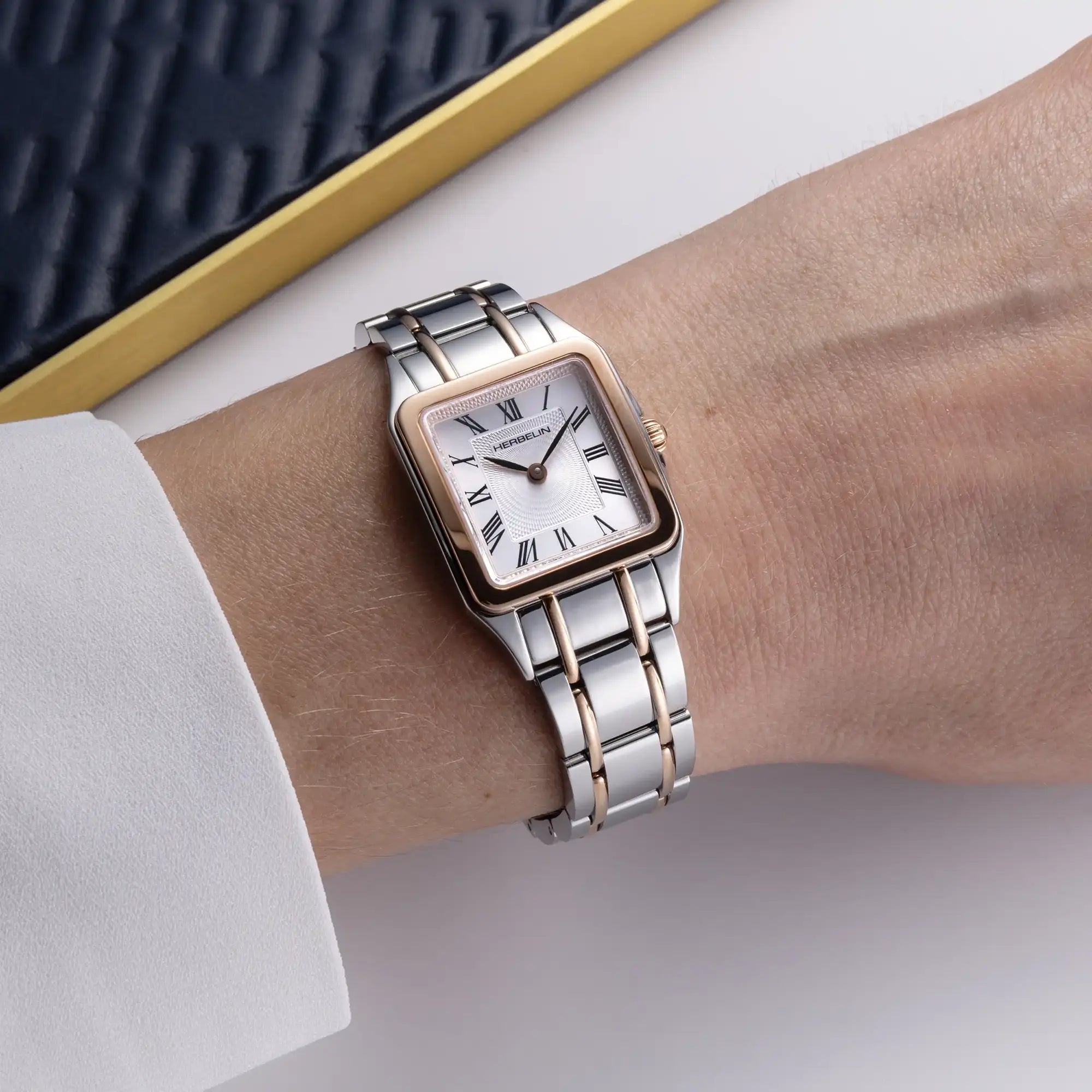 Au poignet féminin, cadran argent guilloché et bracelet acier PVD or rose visibles