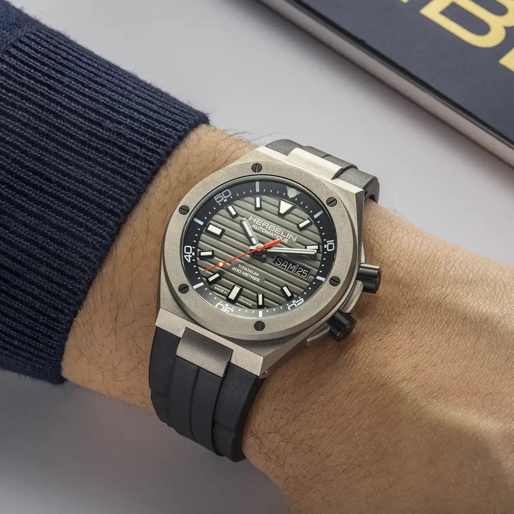 Au poignet masculin, cadran titane mat et bracelet caoutchouc visibles