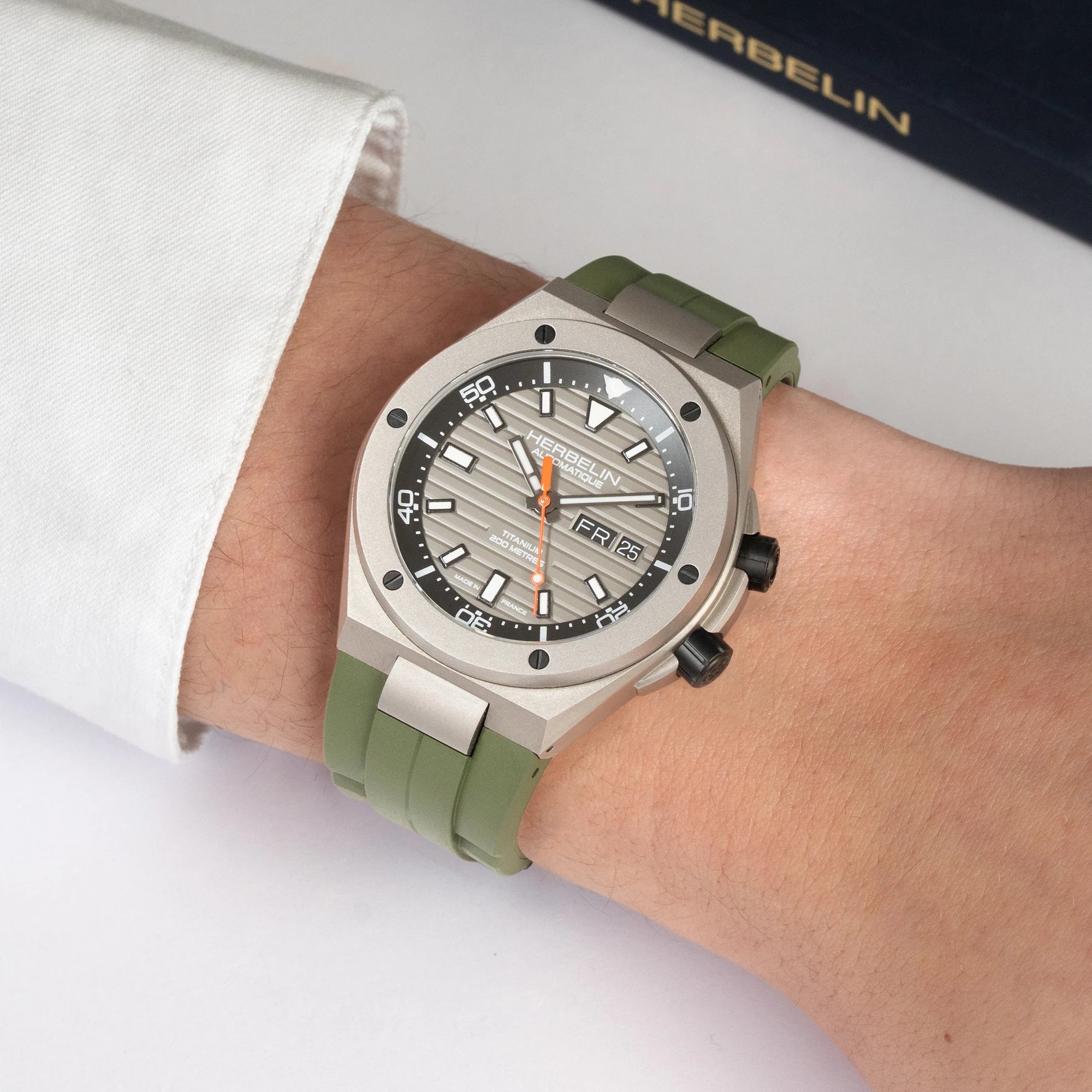 Au poignet masculin, cadran gris titane et bracelet caoutchouc kaki visibles