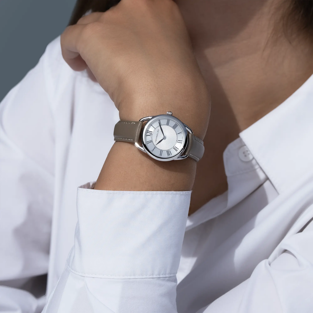 On a feminine wrist, visible white silver guilloché dial and leather strap