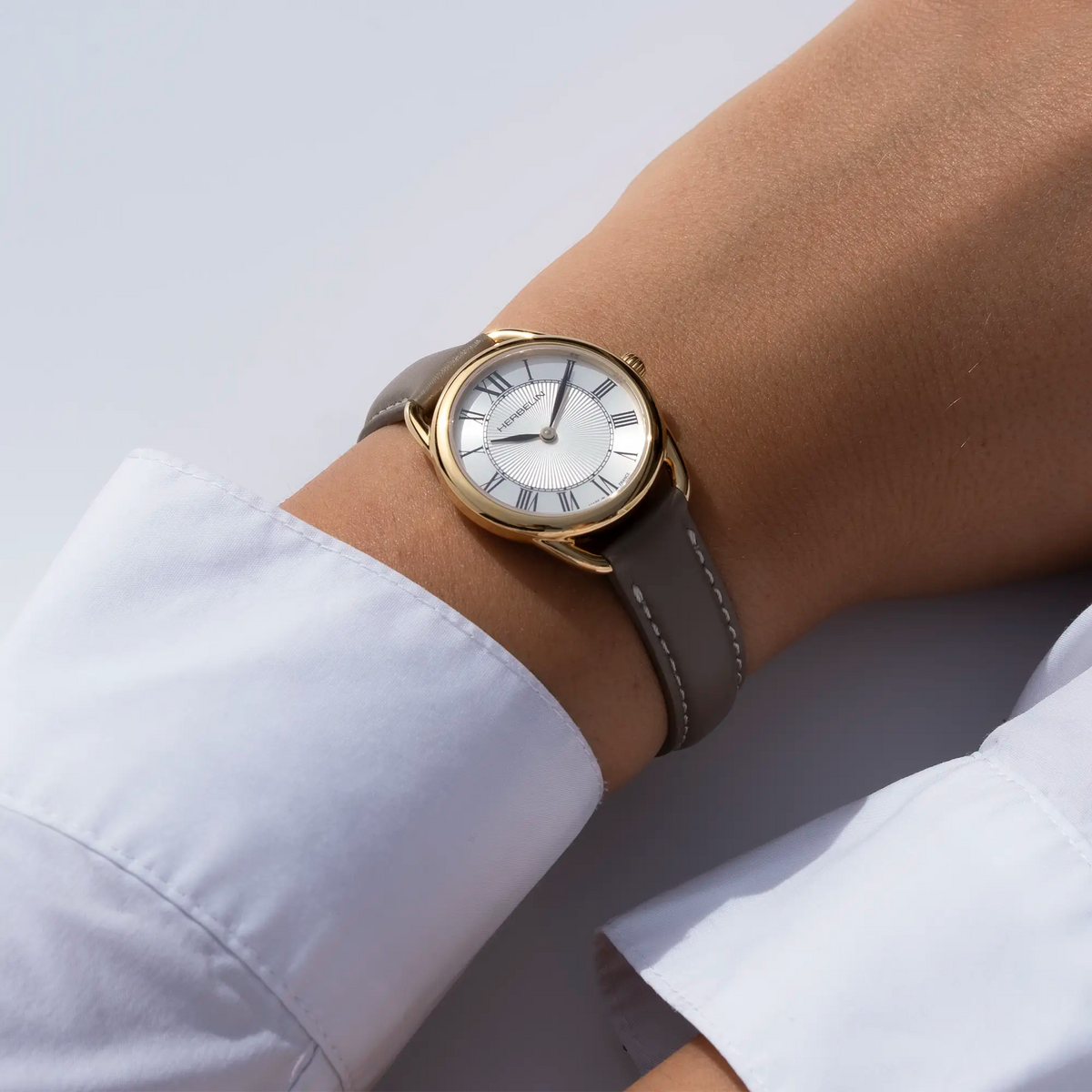 On a feminine wrist, visible white silver guilloché dial and leather strap