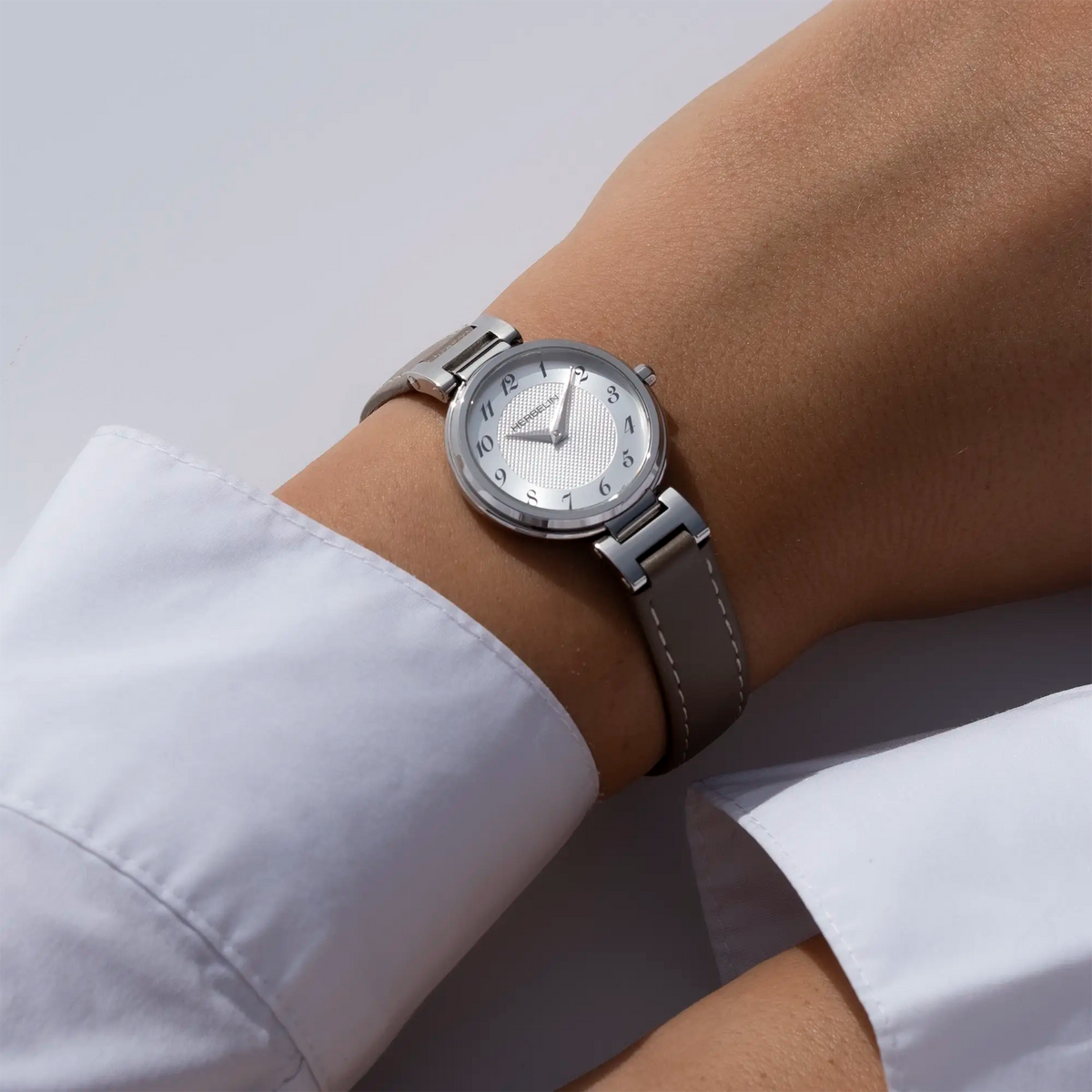 Autre vue au poignet féminin, cadran argent blanc guilloché et bracelet cuir visibles