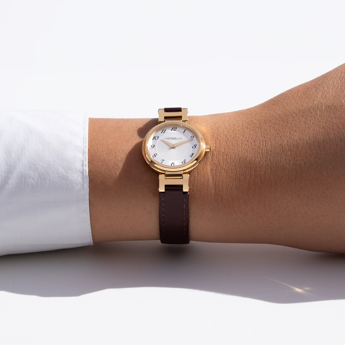 Au poignet féminin, cadran argent blanc guilloché et bracelet cuir visibles