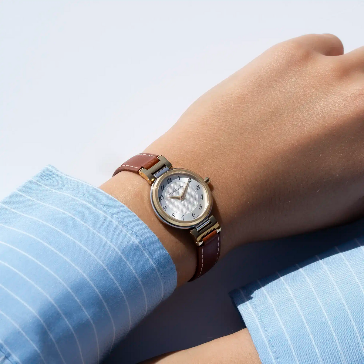 Autre vue au poignet féminin, cadran argent blanc guilloché et bracelet cuir visibles