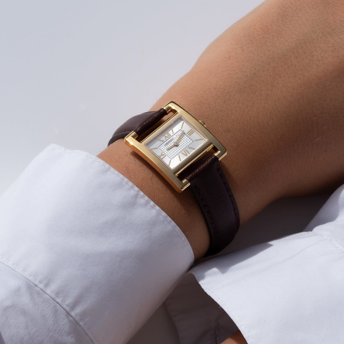 Au poignet féminin, cadran argent blanc guilloché et bracelet cuir visibles