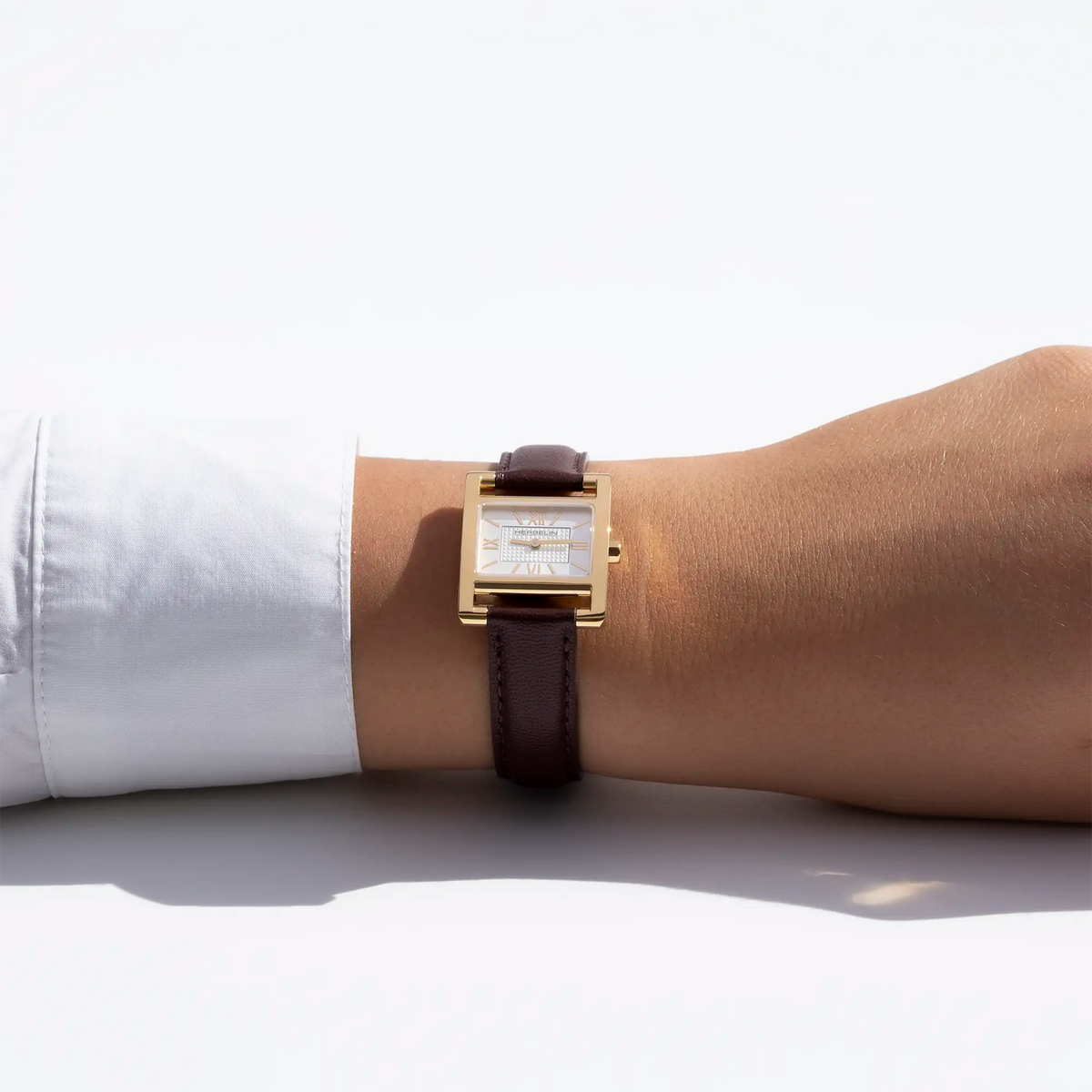 On a feminine wrist, visible white silver guilloché dial and leather strap