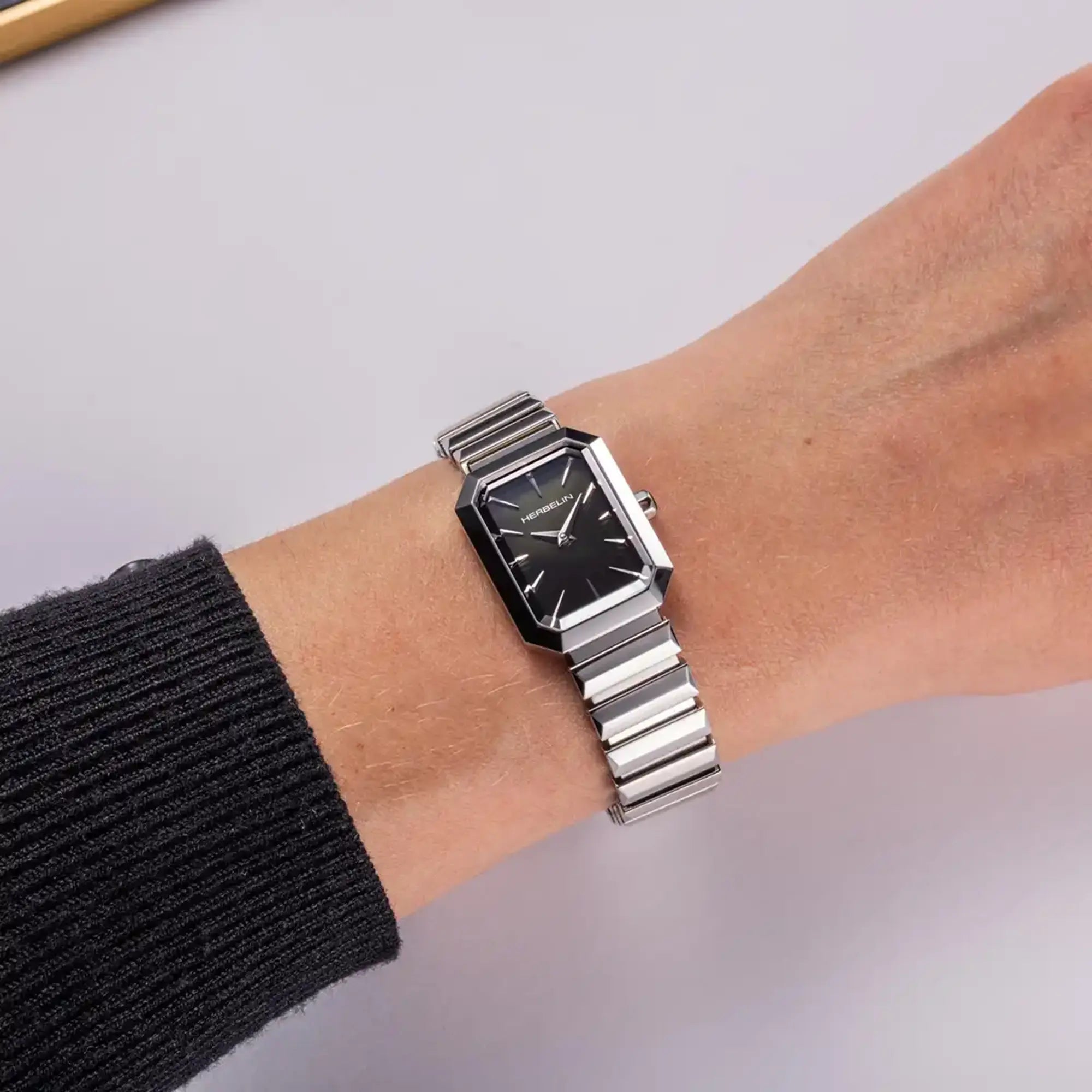 Au poignet féminin, cadran nacre noire et bracelet acier visibles