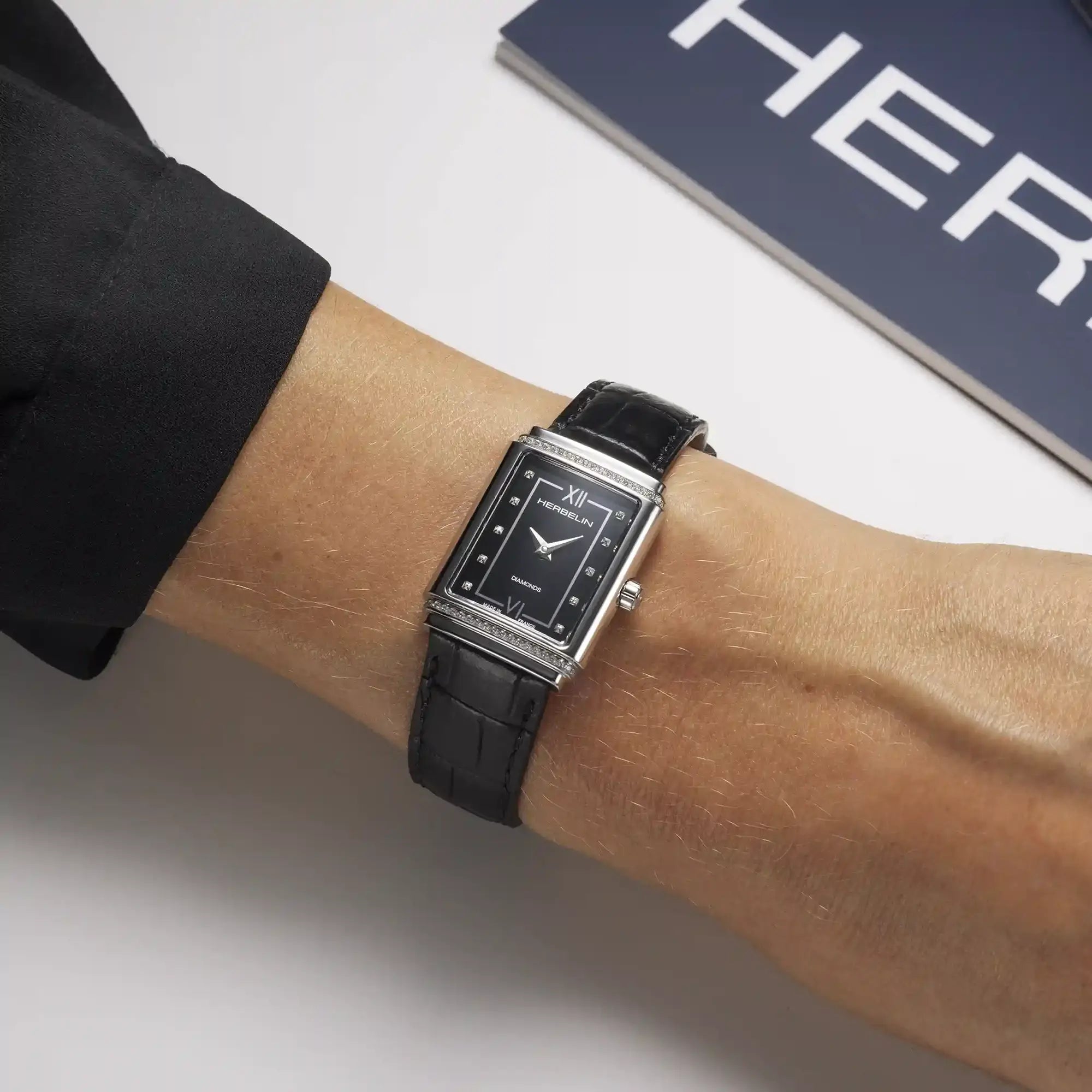 Au poignet féminin, cadran diamants et bracelet cuir visibles